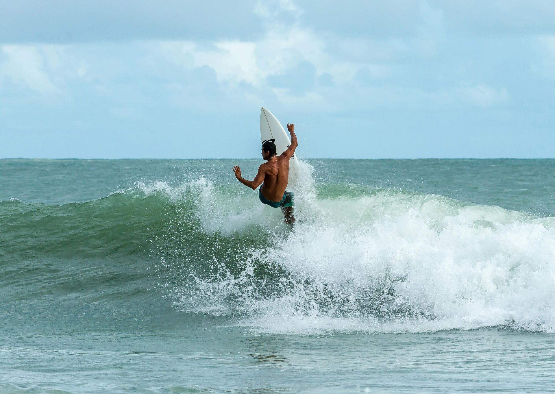 Surfer on a wave, arms up, in the ocean.