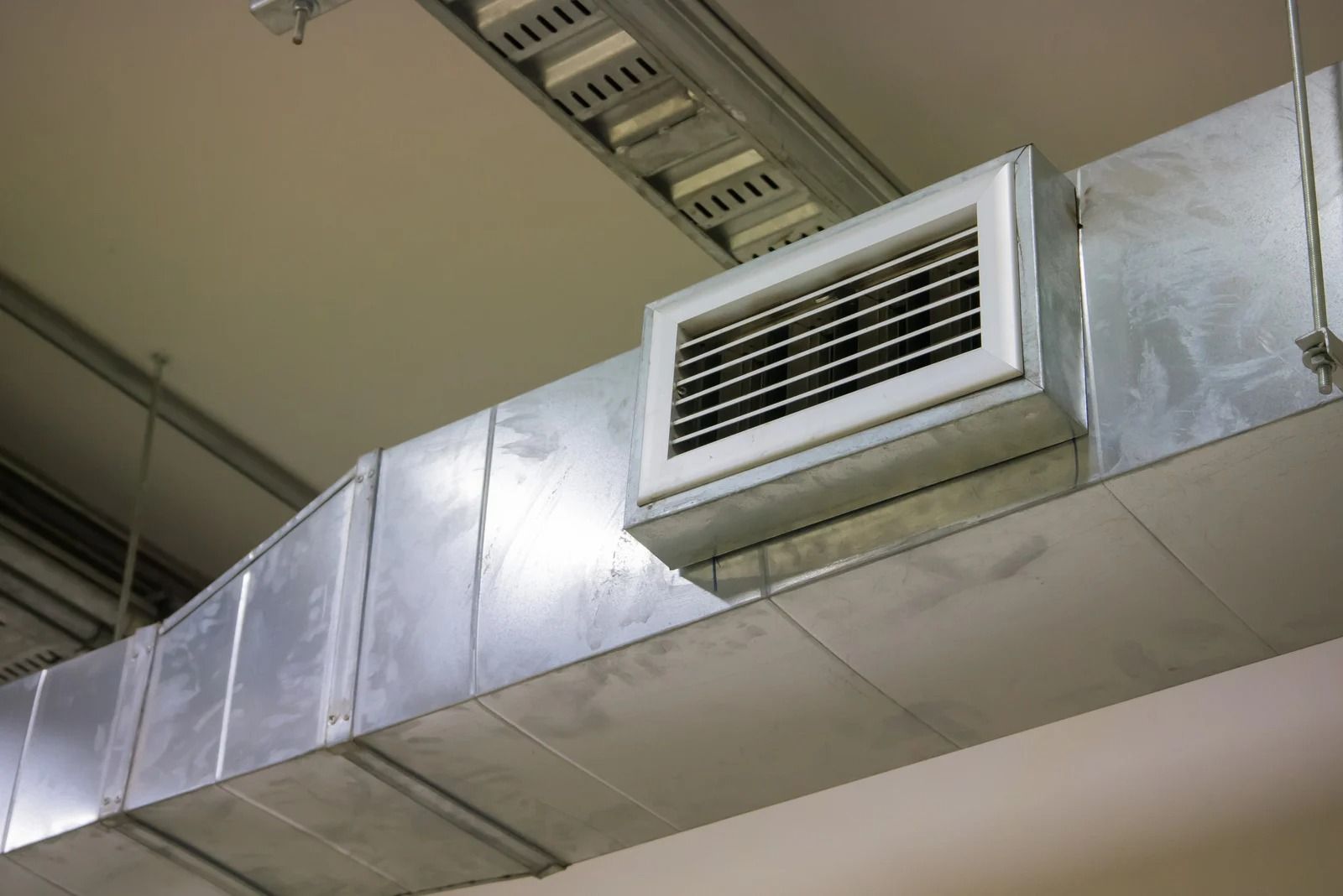 Silver ventilation duct and vent on a ceiling.