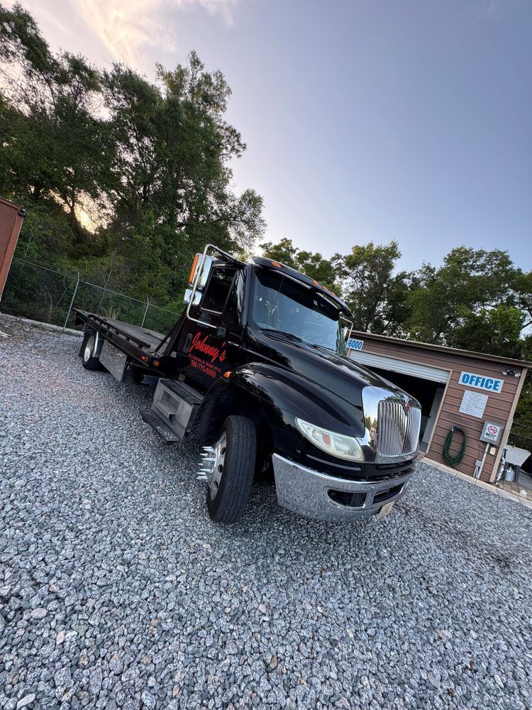 Black tow truck parked on gravel. 
