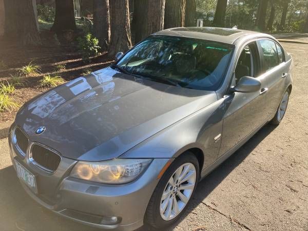 A silver bmw is parked on the side of the road.
