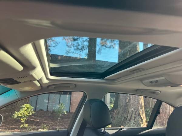 A car with a sunroof is parked in front of a house.