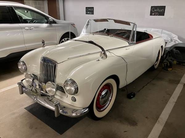 A white car is parked in a garage next to a white car.