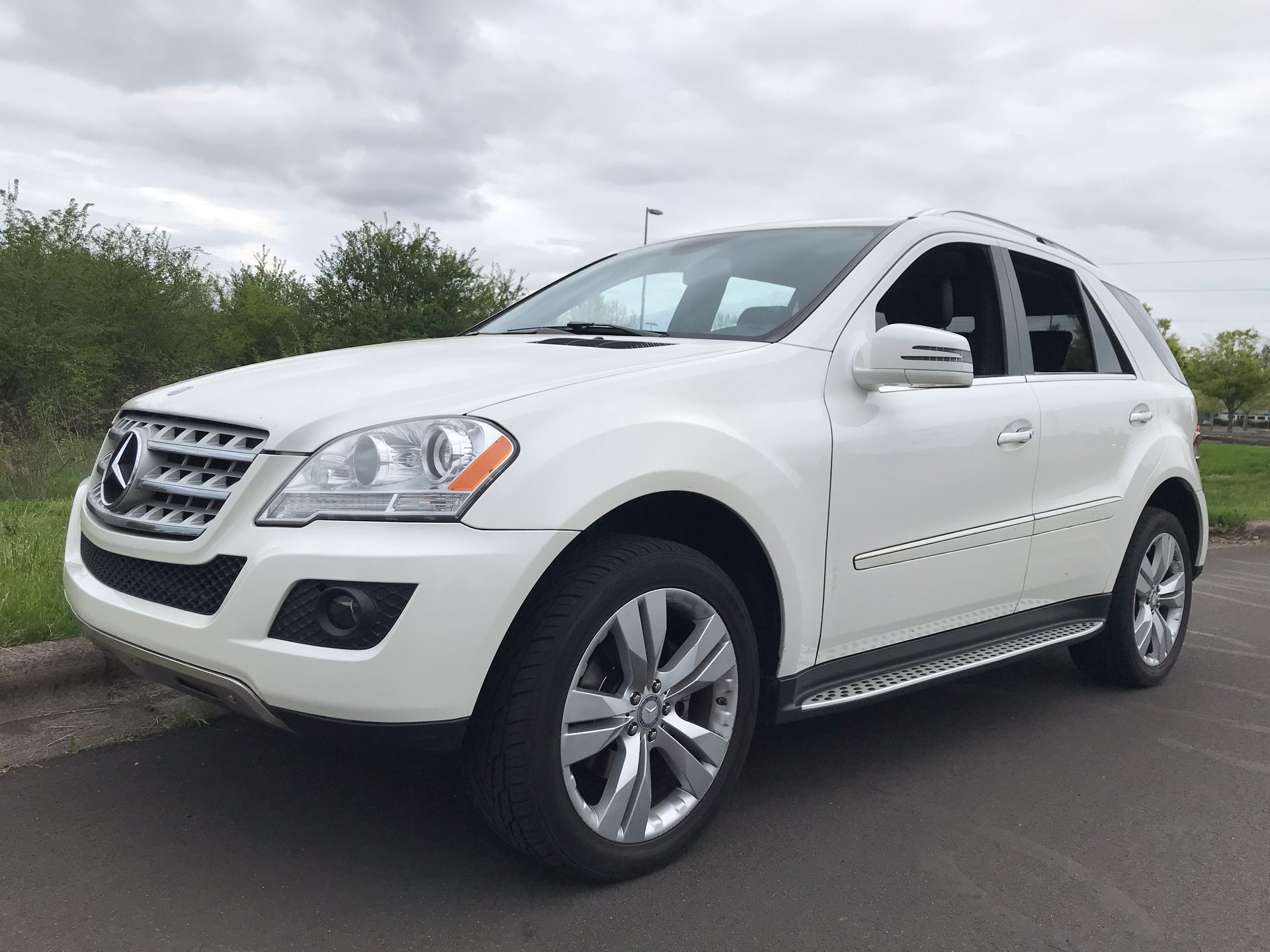 A white mercedes benz ml 350 is parked on the side of the road.