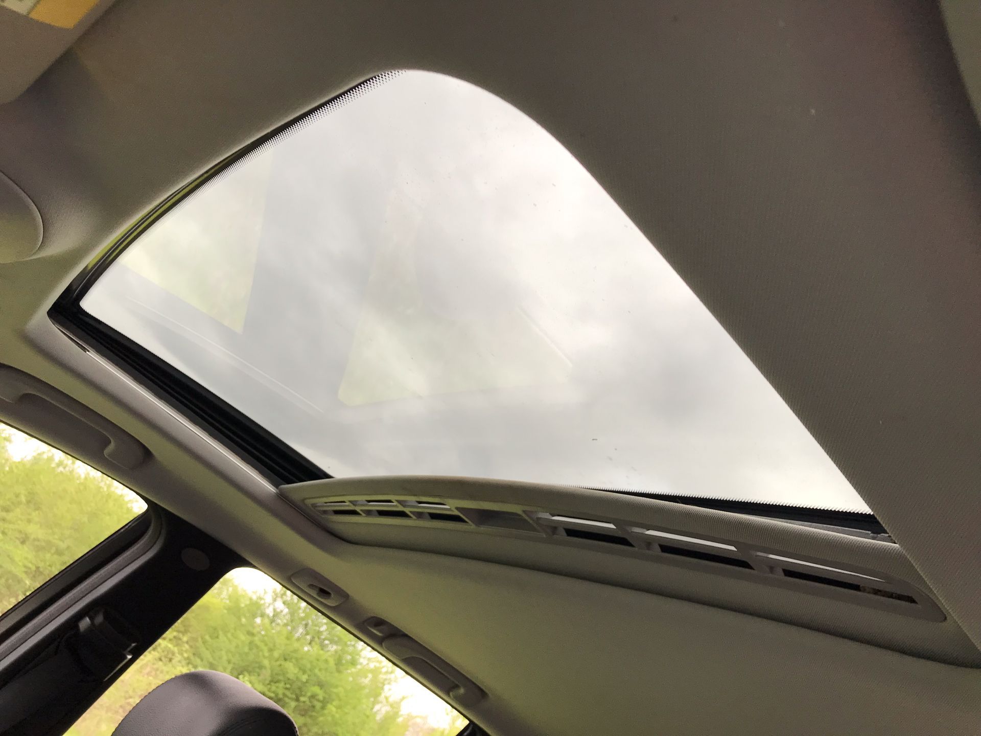 The sunroof of a car with a cloudy sky in the background