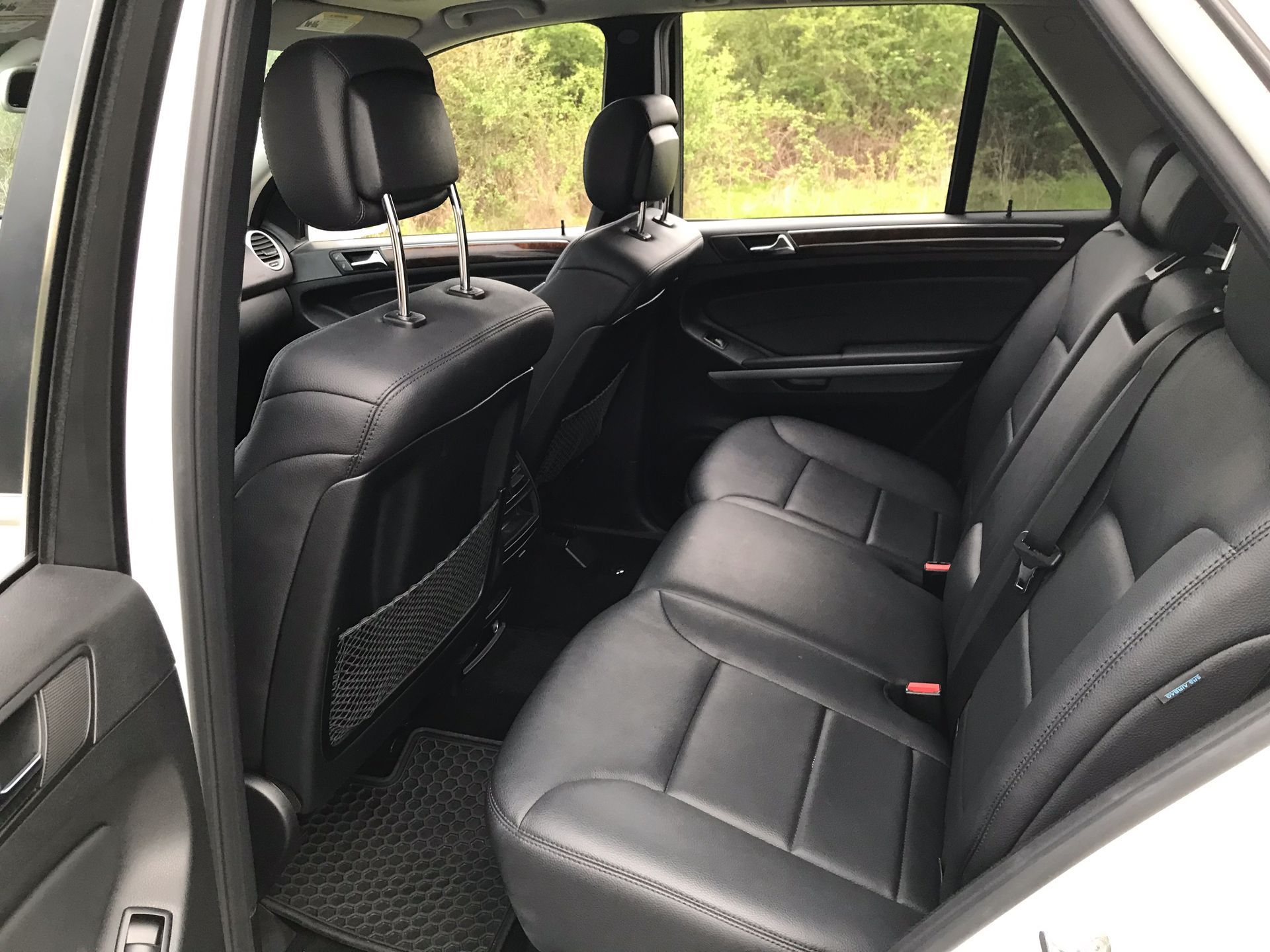 The back seat of a white car with black leather seats.