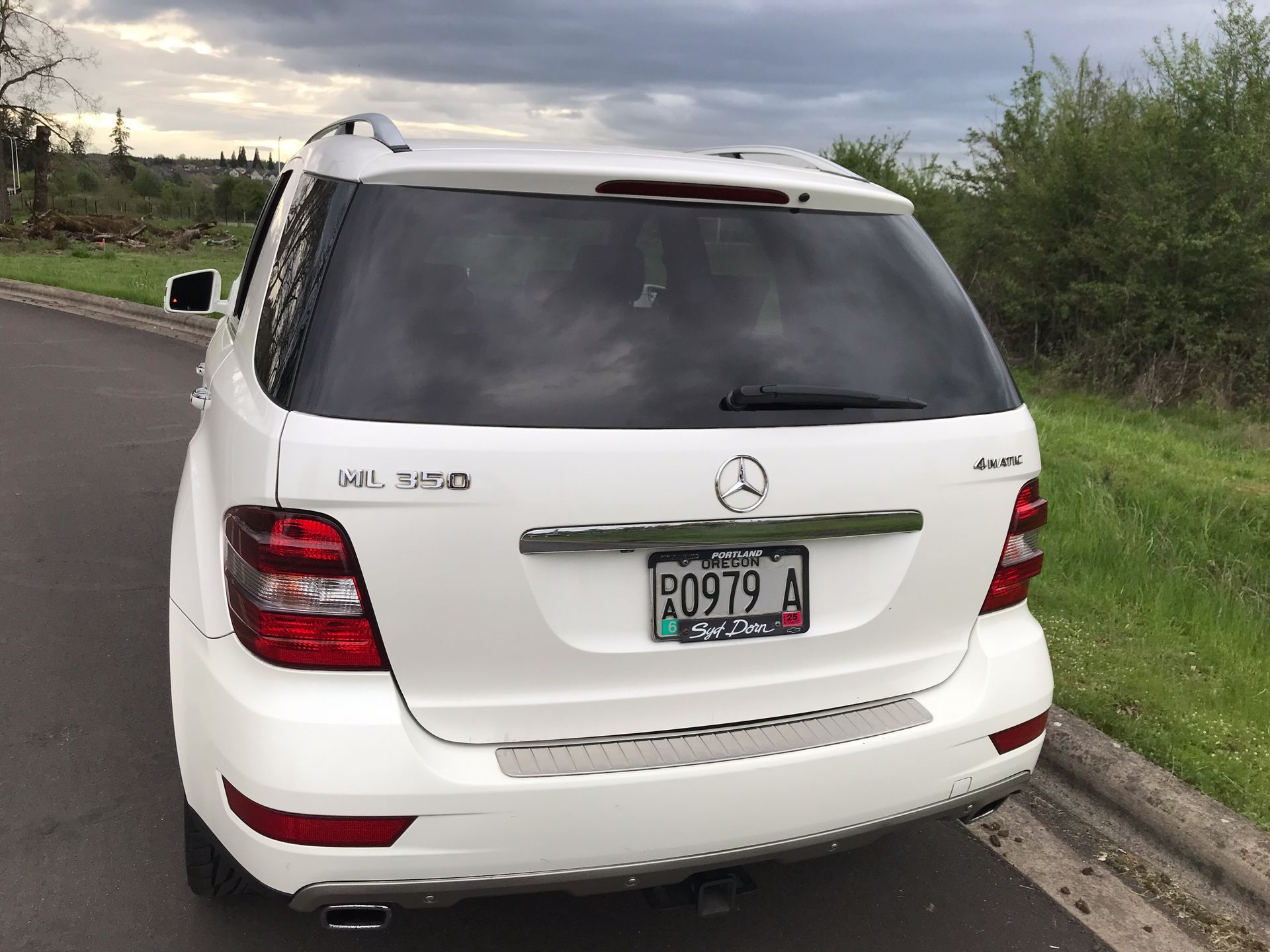 A white mercedes benz is parked on the side of the road