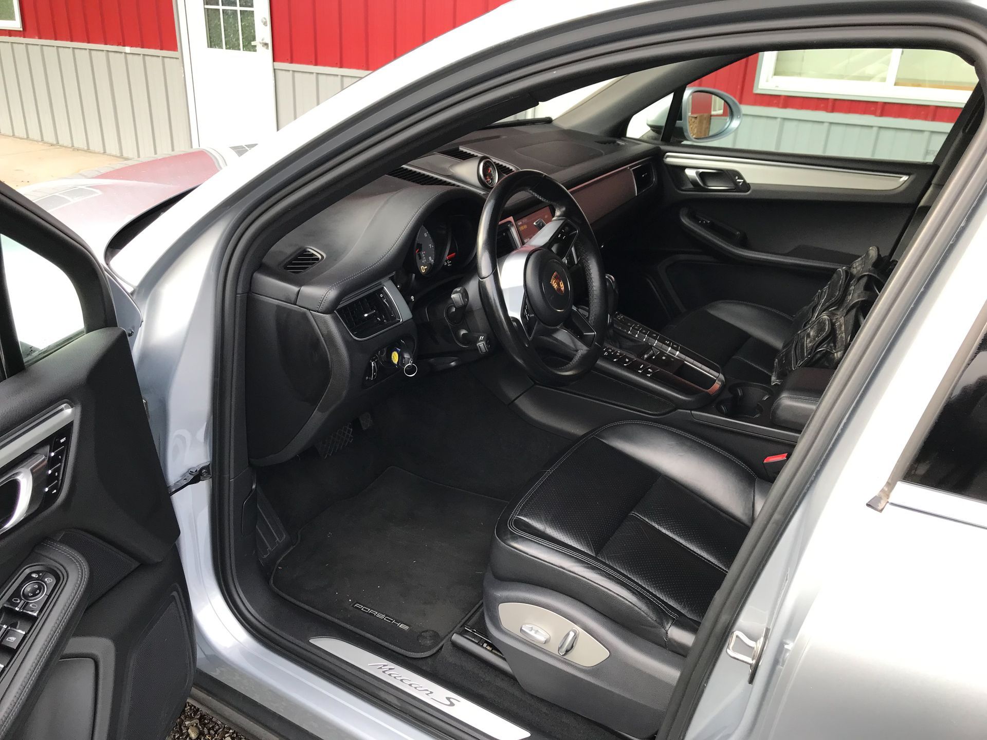 The interior of a porsche macan is shown with the door open.
