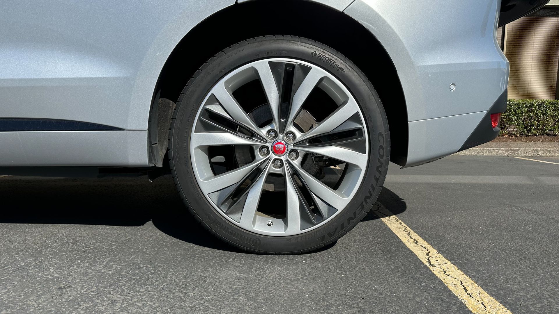 A silver car is parked in a parking lot next to a yellow line.