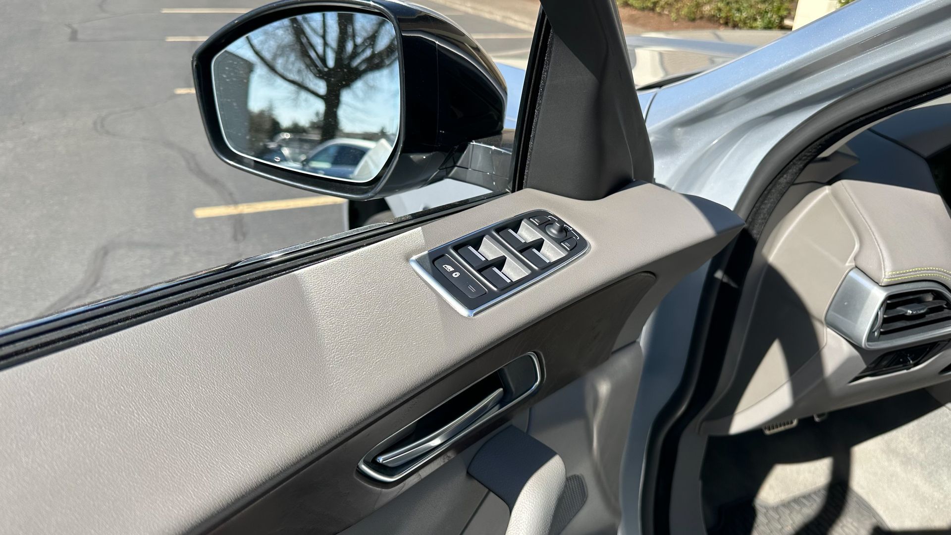 The inside of a car with the door open and a rear view mirror.
