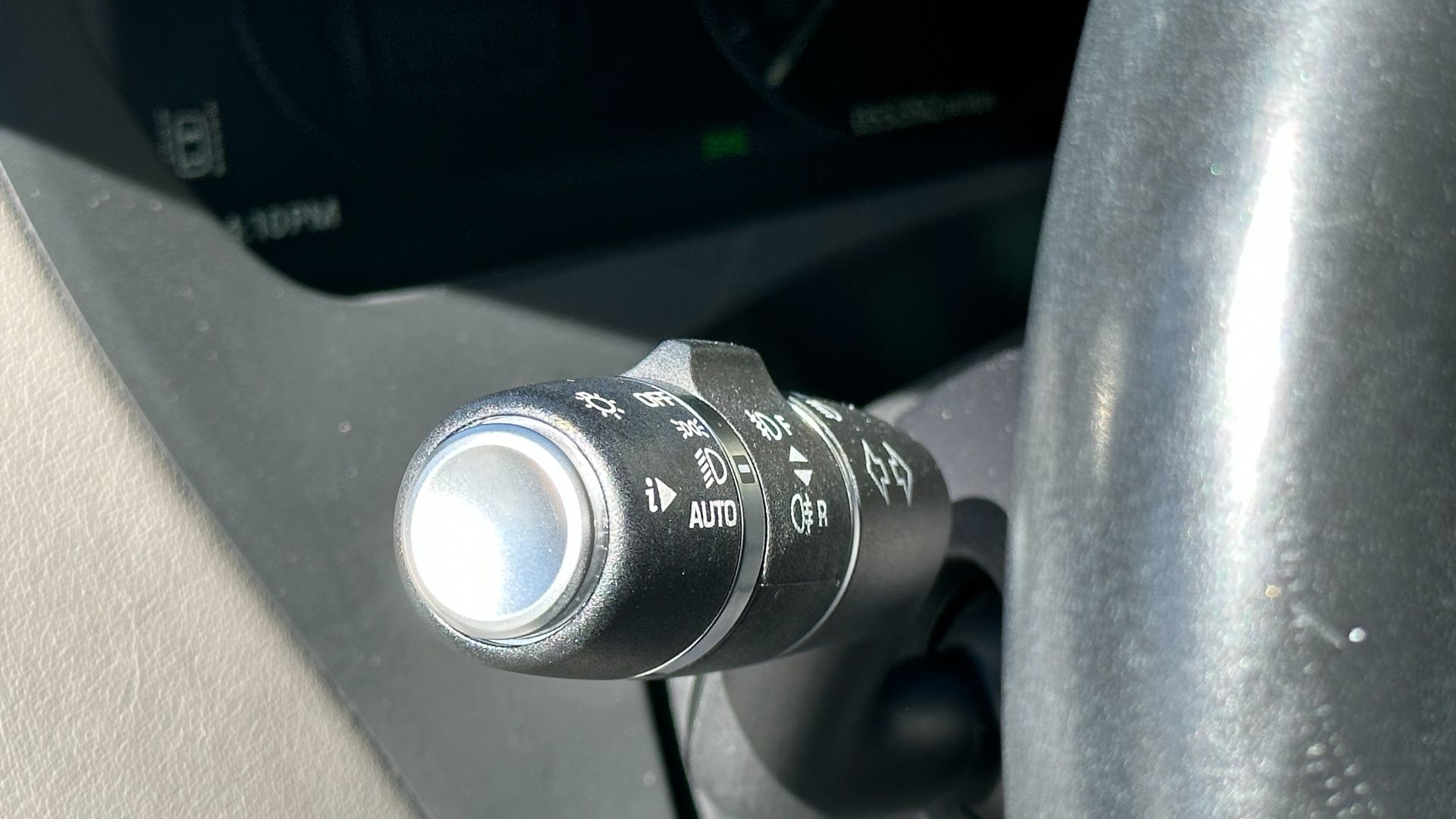 A close up of a light switch on a car steering wheel.