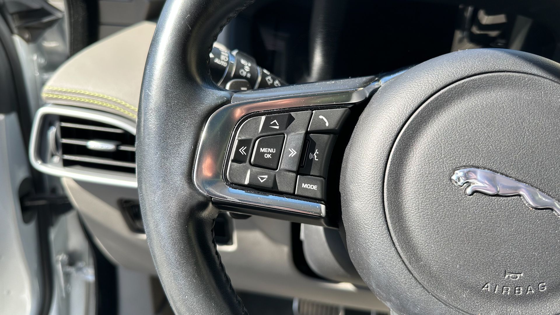 A close up of a car steering wheel with a jaguar logo on it