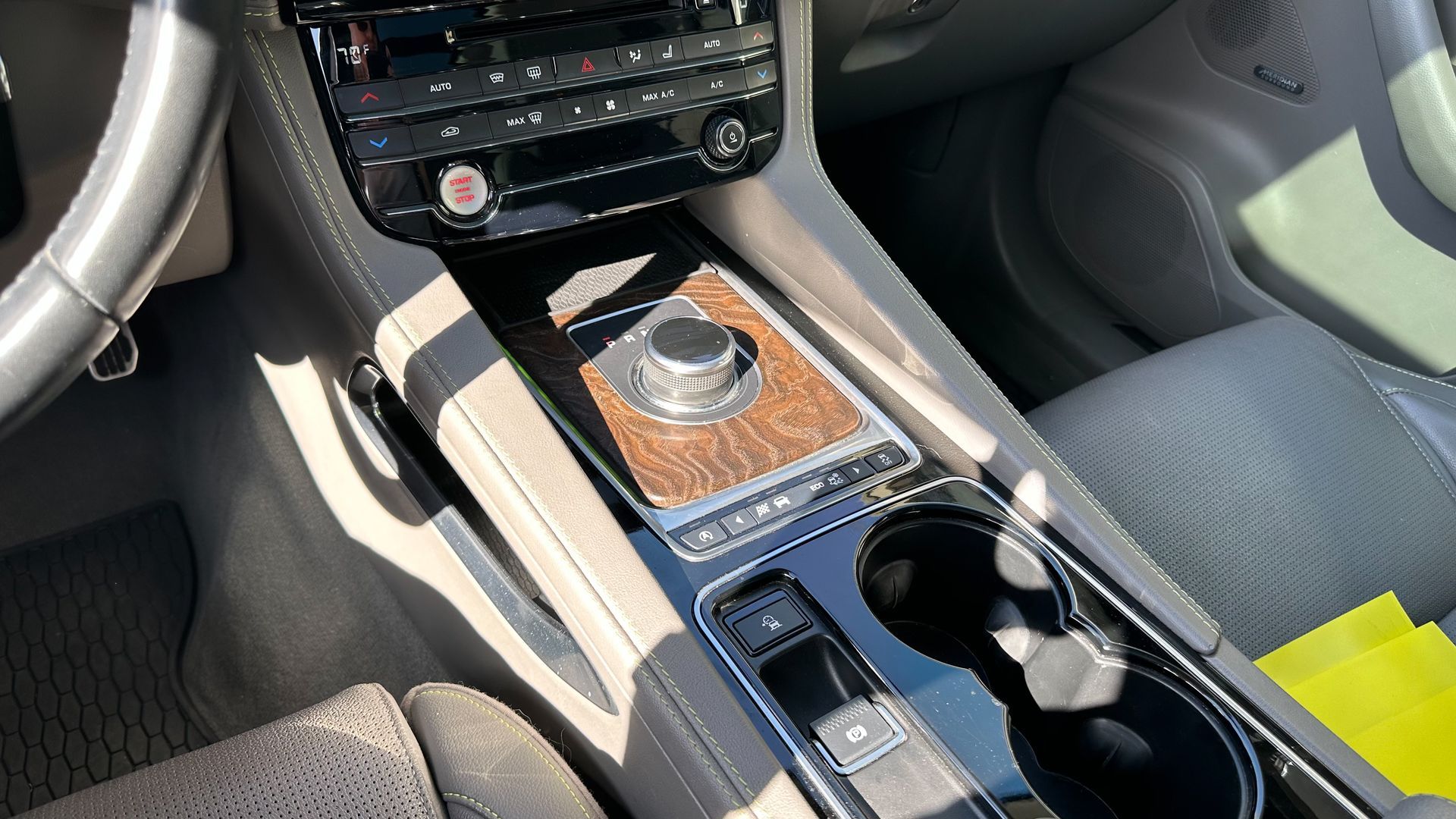 The interior of a car with a steering wheel and a cup holder.