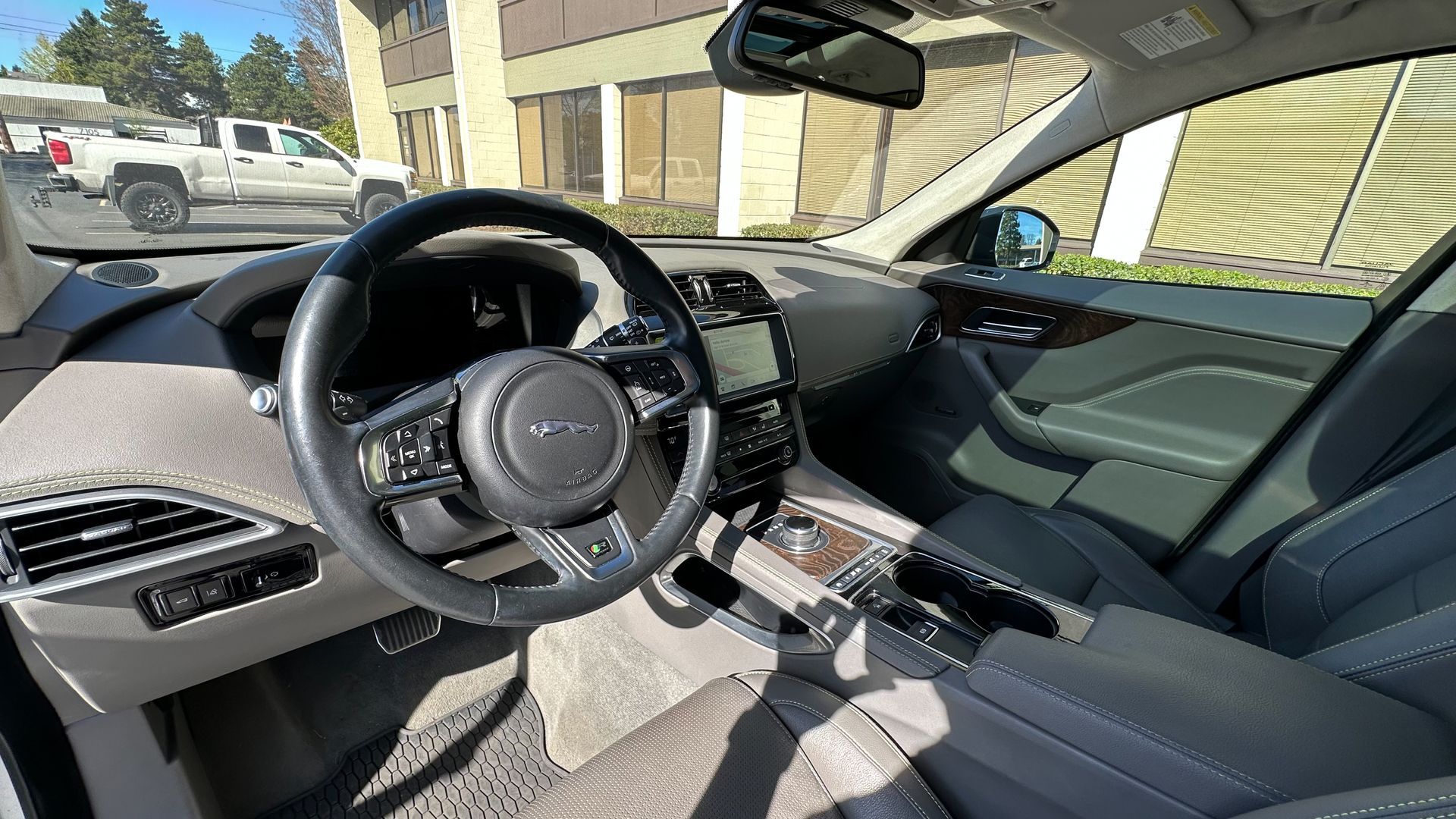 The interior of a car with a steering wheel and a rear view mirror.