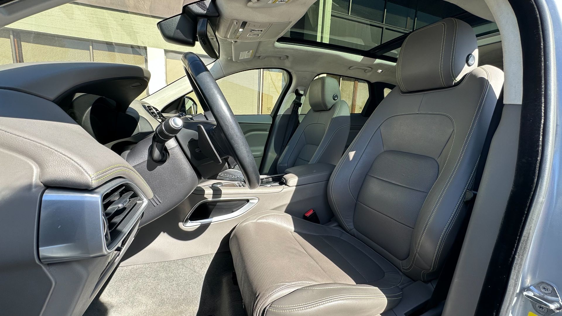 The interior of a car with a sunroof and leather seats.