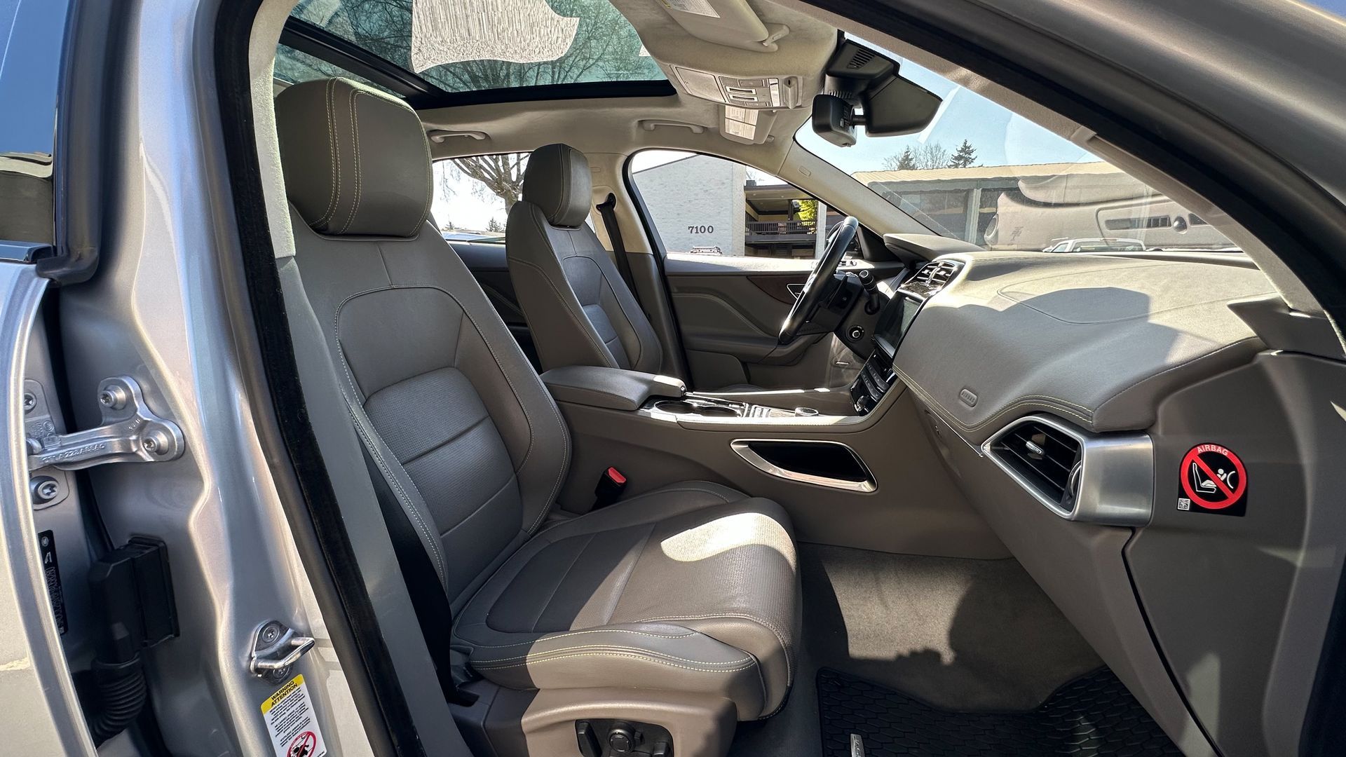 The interior of a silver car with the sunroof open.