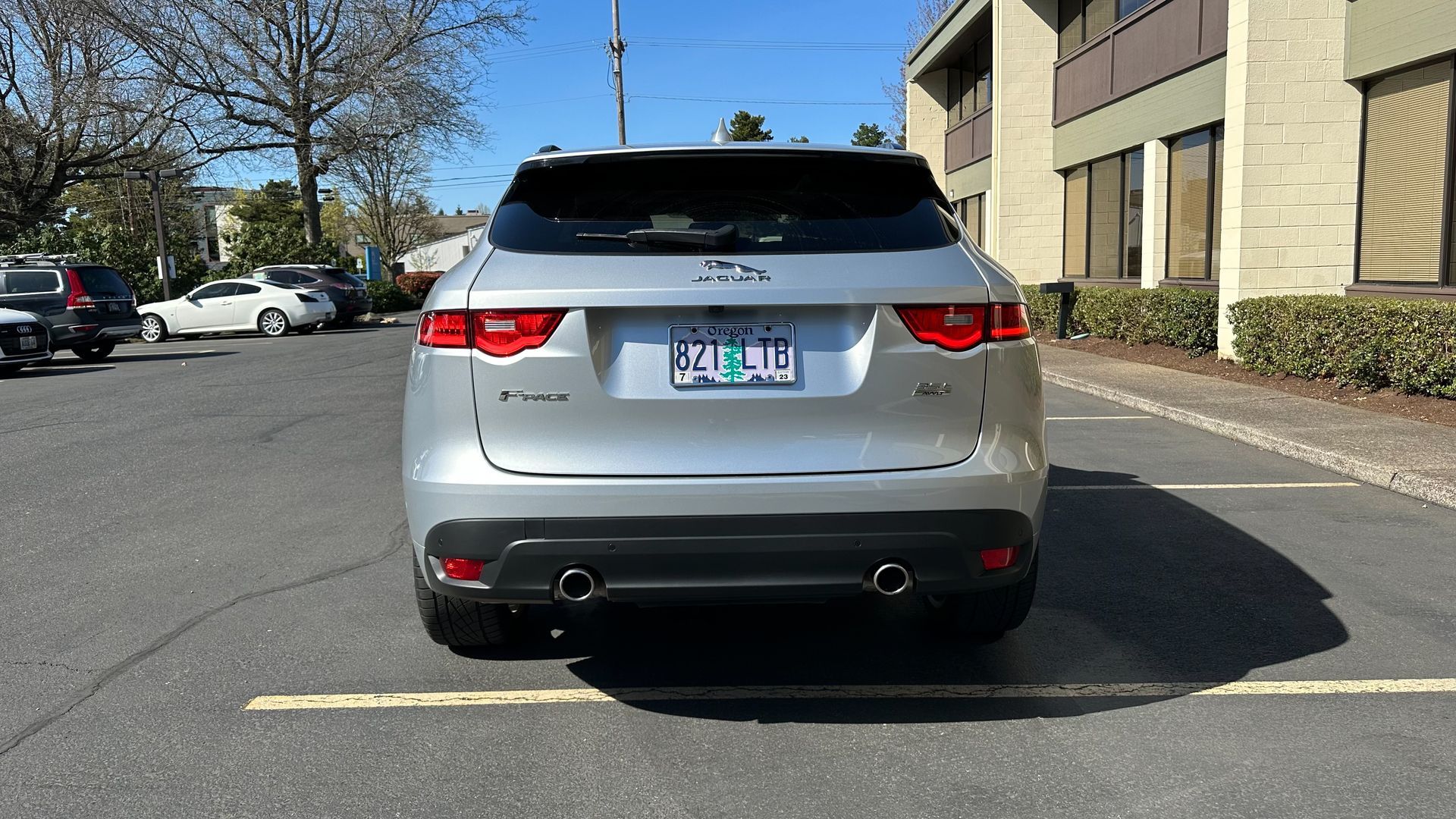 A silver jaguar f pace is parked in a parking lot