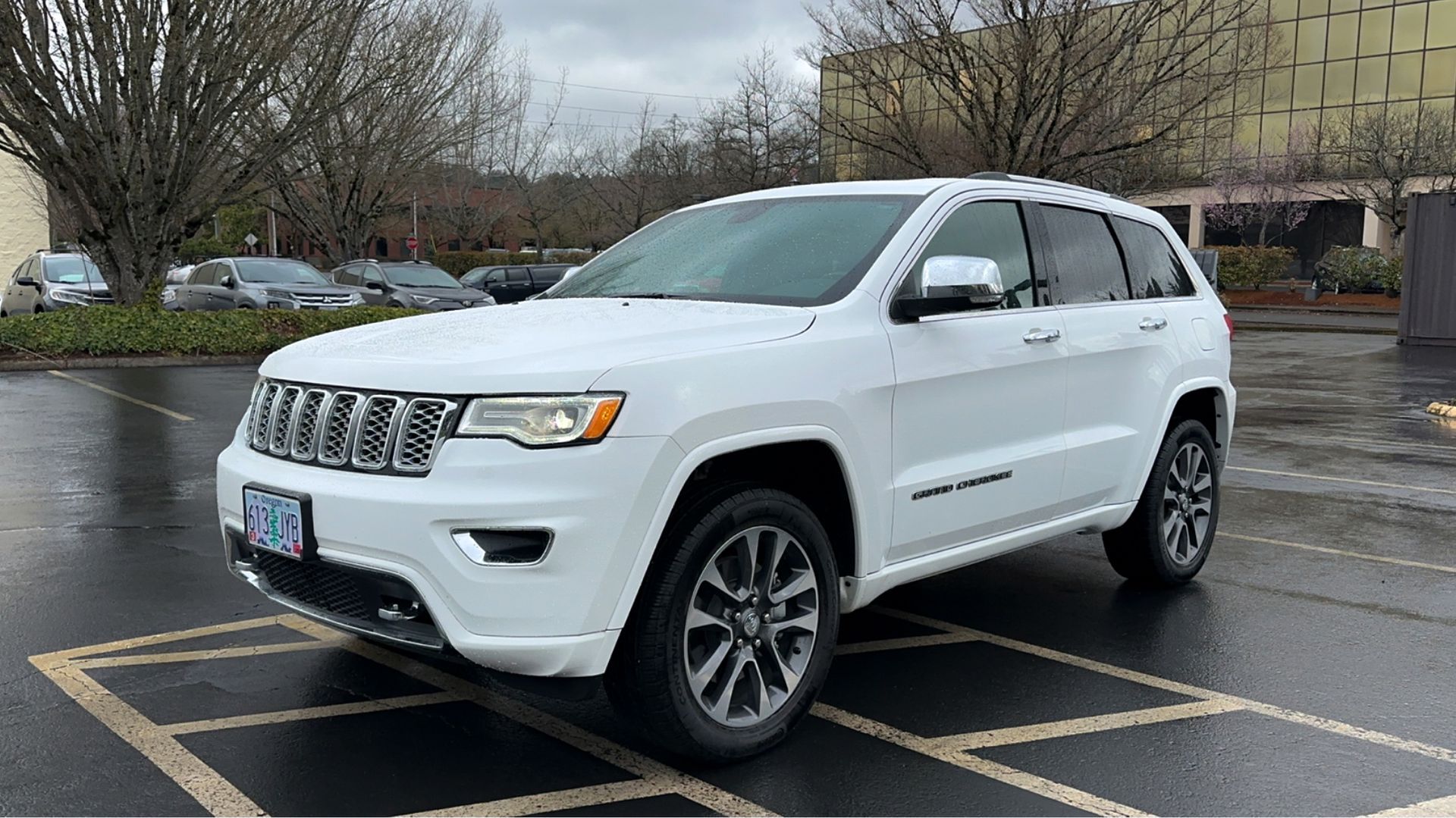 A white jeep grand cherokee is parked in a parking lot.