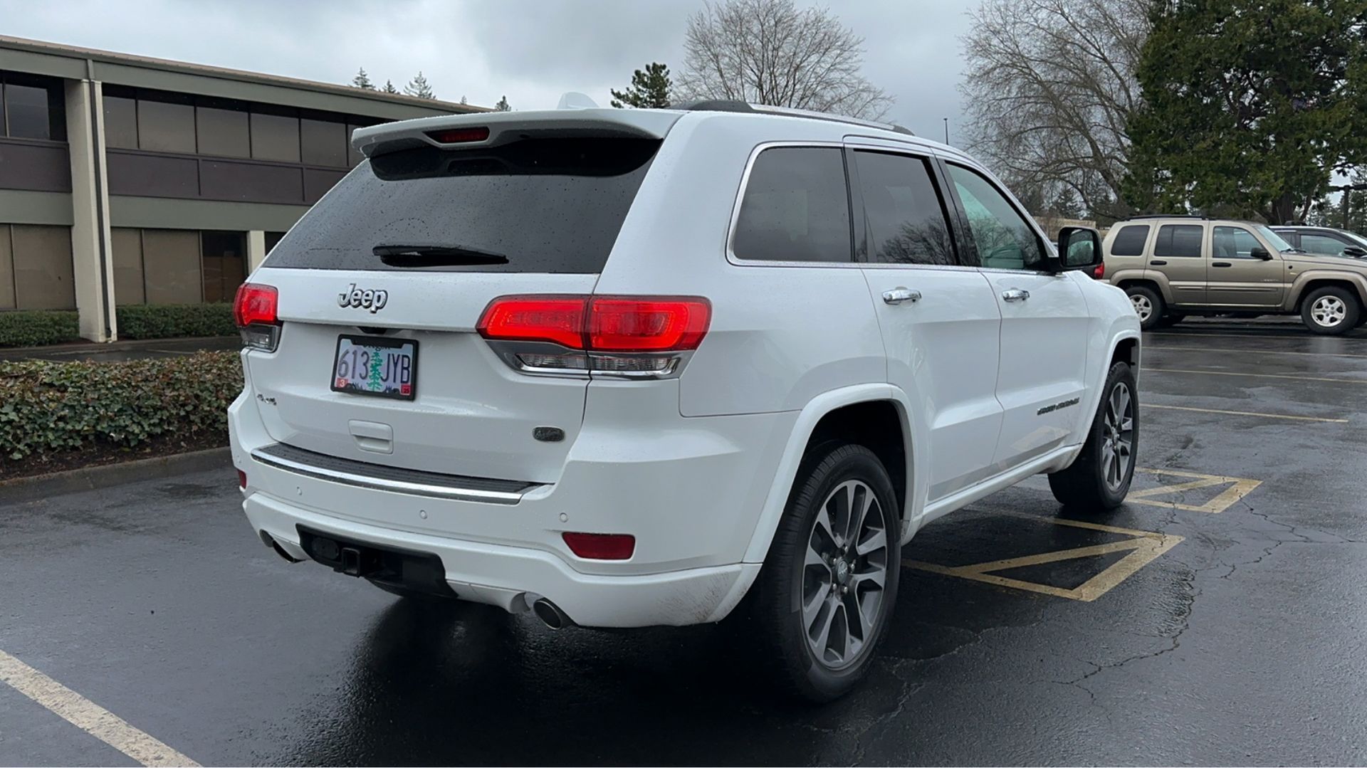 A white jeep grand cherokee is parked in a parking lot.
