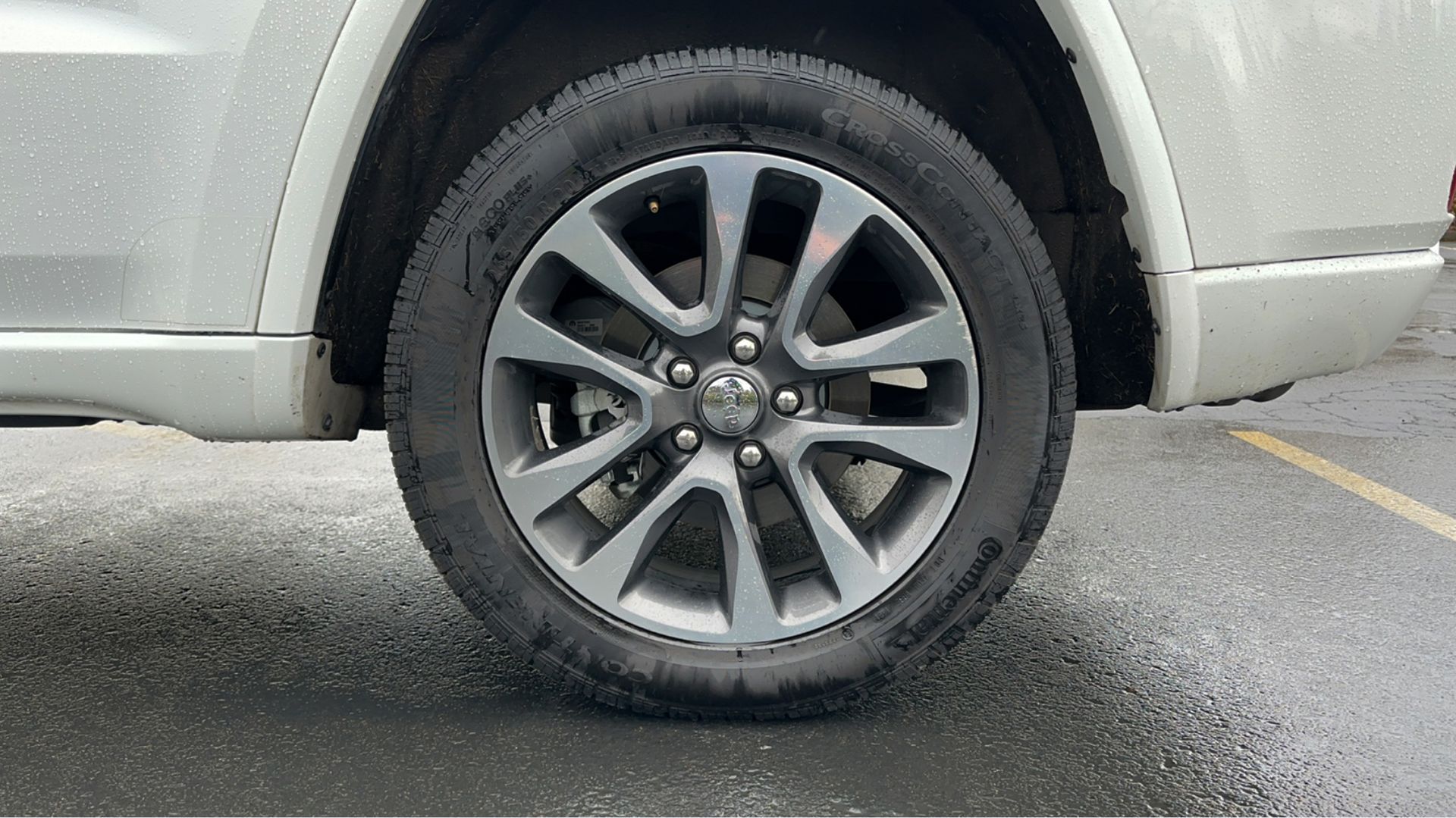 A close up of a car wheel in a parking lot.
