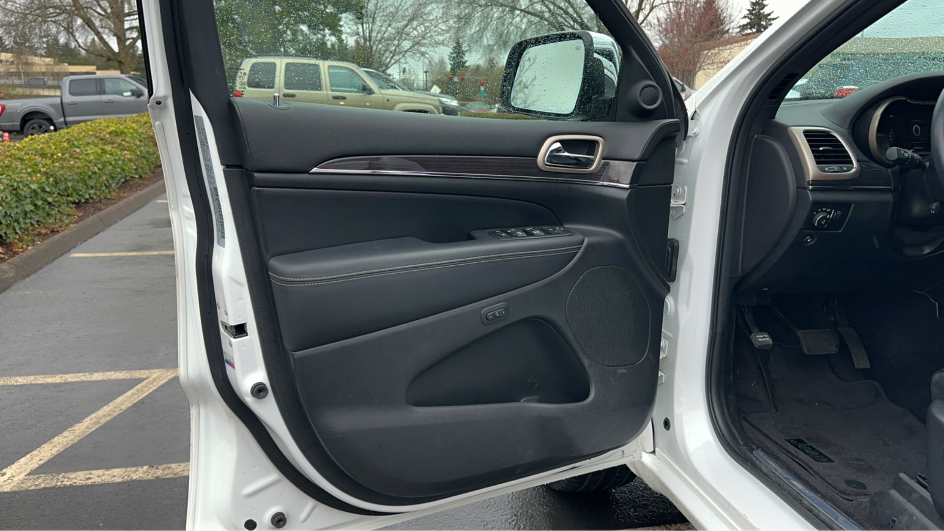 A white car is parked in a parking lot with the door open.
