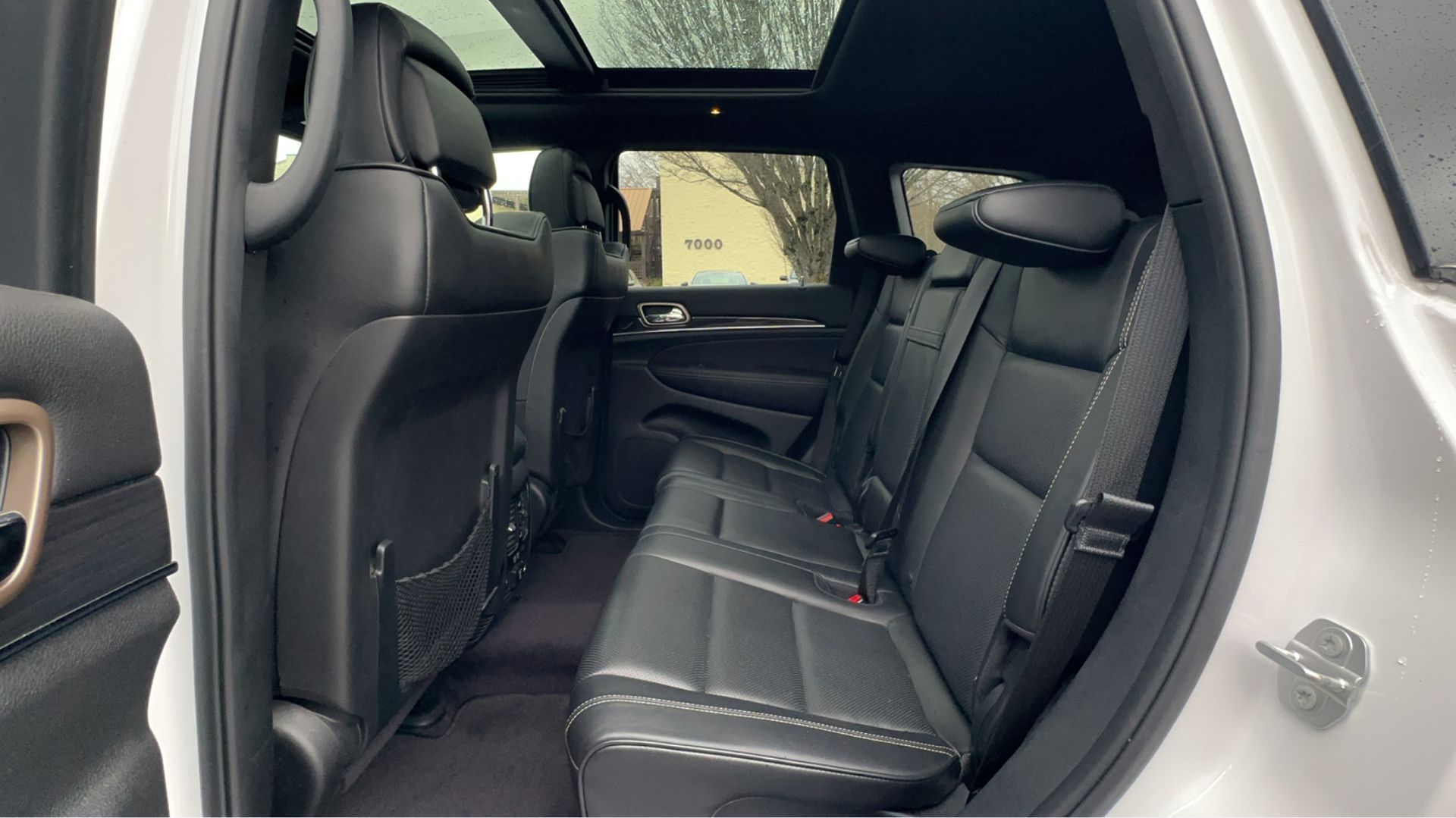 The back seat of a white jeep grand cherokee with a sunroof.