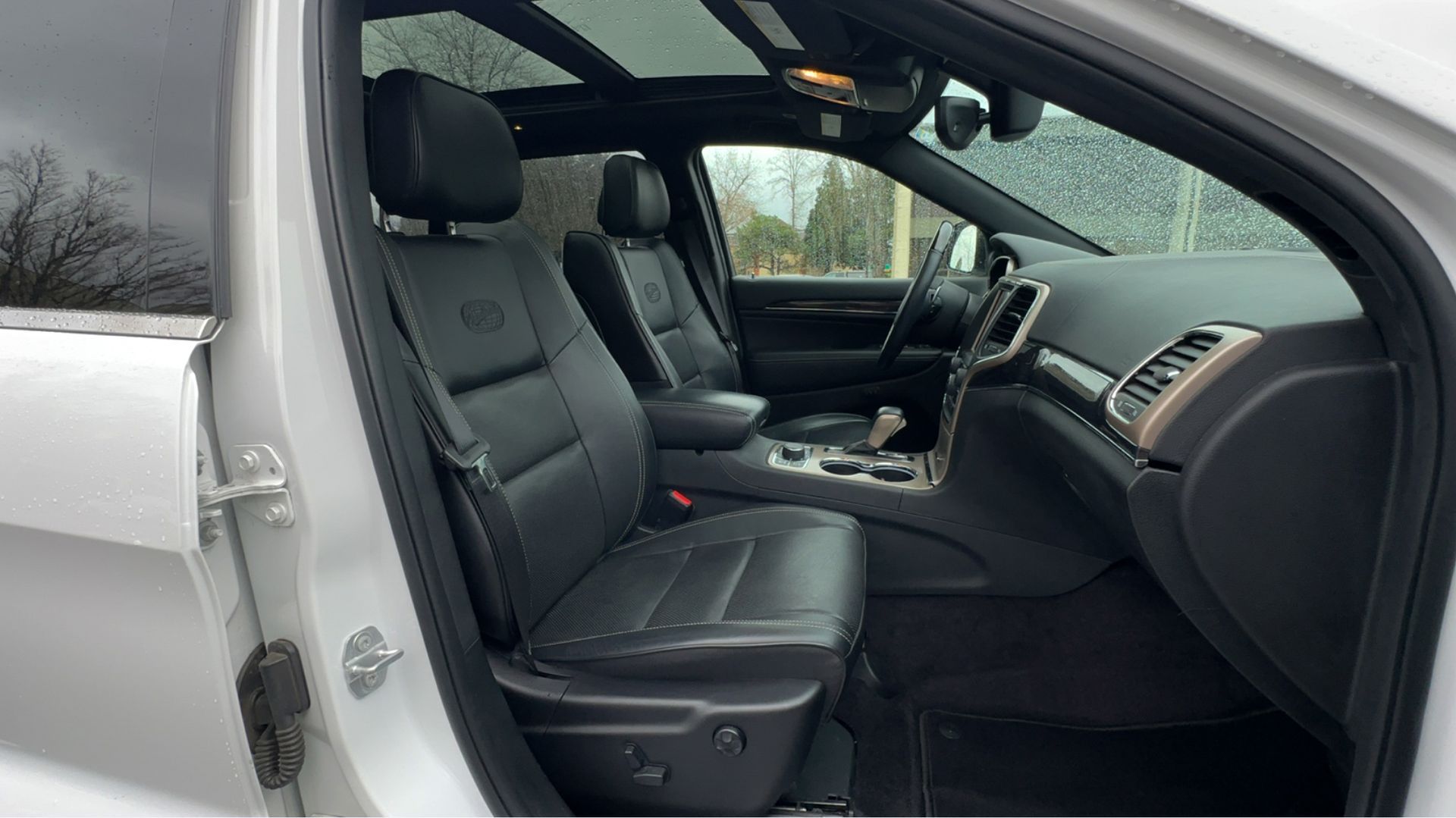 The interior of a white jeep grand cherokee with black leather seats.