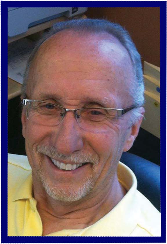 A man wearing glasses and a yellow shirt is smiling