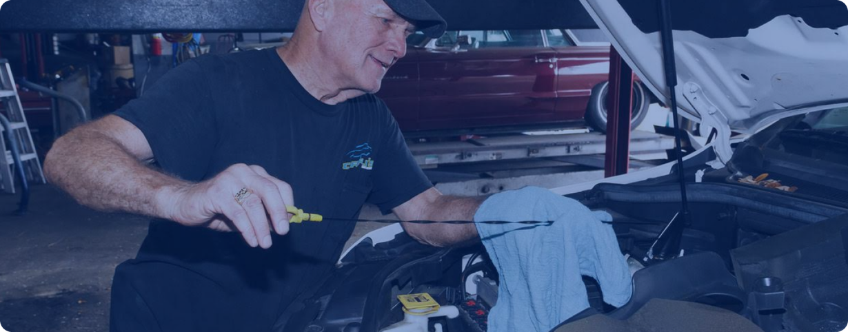 Mechanic working under an open car hood with a blue cloth draped over the engine area | Charlie's Car Care