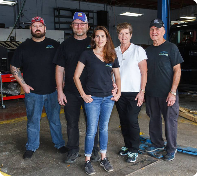 Five people standing together in a garage, wearing casual clothes and work shirts. | Charlie's Car Care