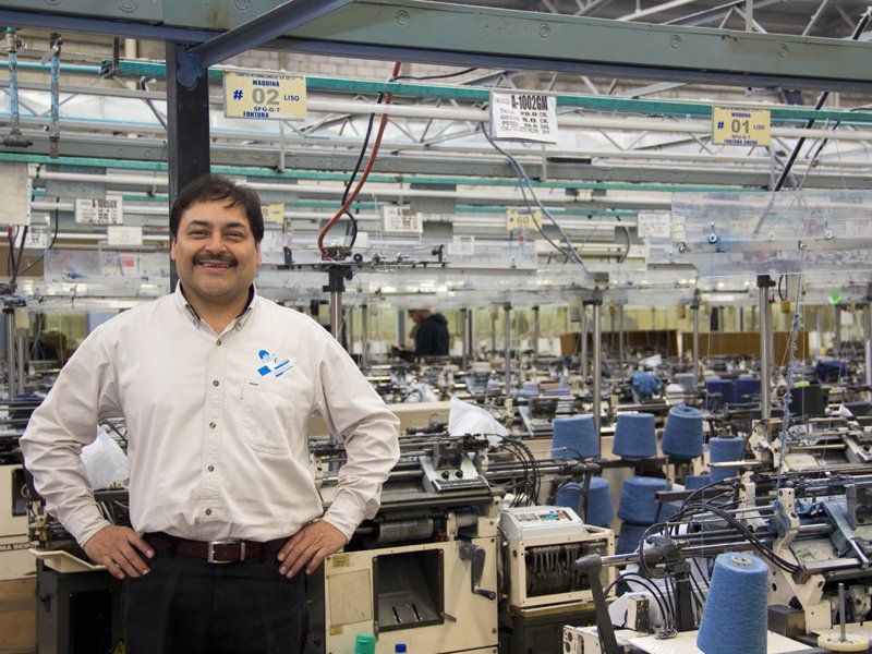 Un hombre está parado en una fábrica con las manos en las caderas