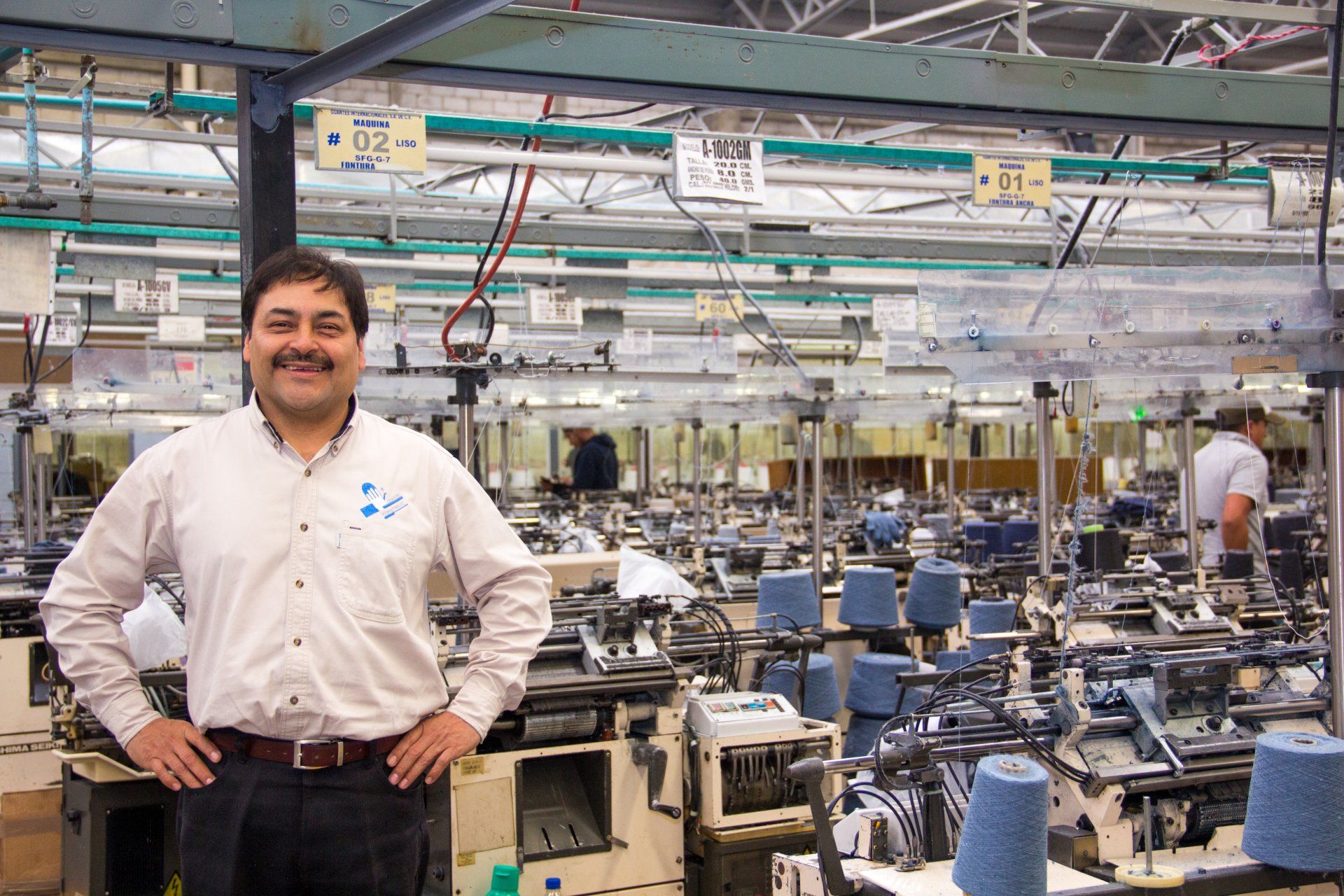 Un hombre está parado en una fábrica con las manos en las caderas