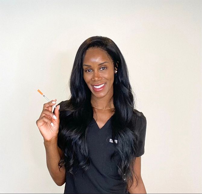 A woman is holding a syringe in her hand and smiling.