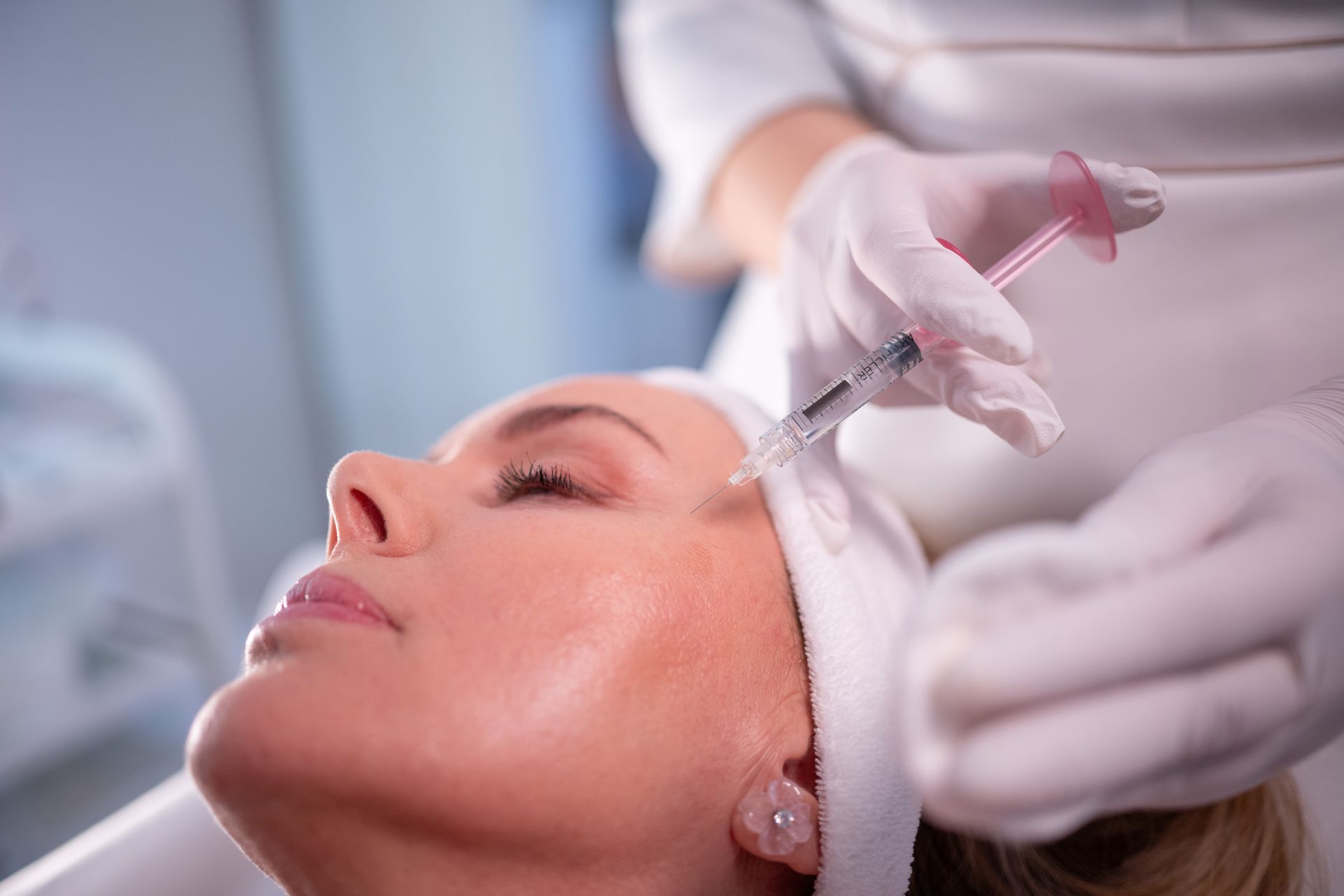 A woman is getting a botox injection in her forehead.