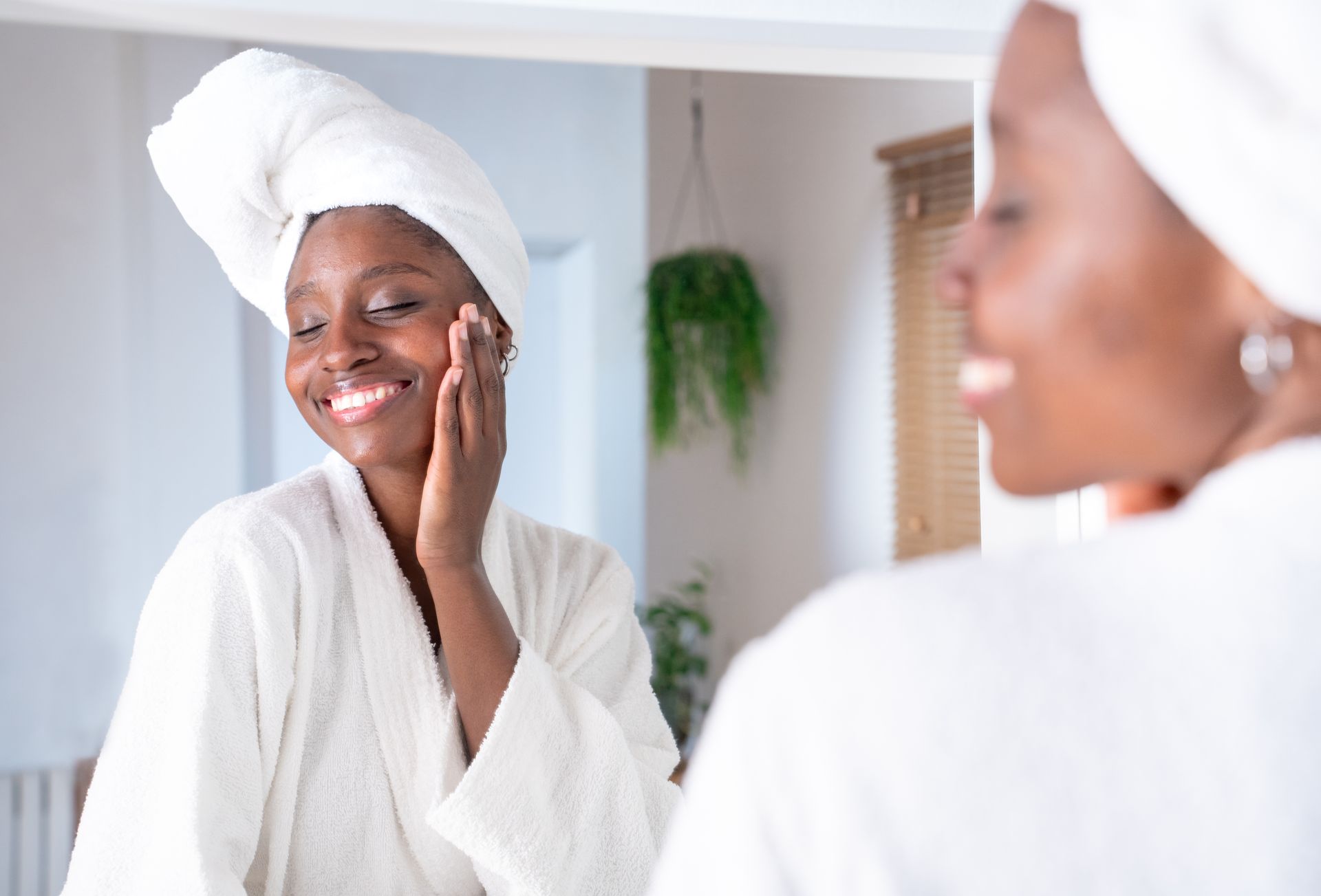 woman looking in mirror at glowing skin