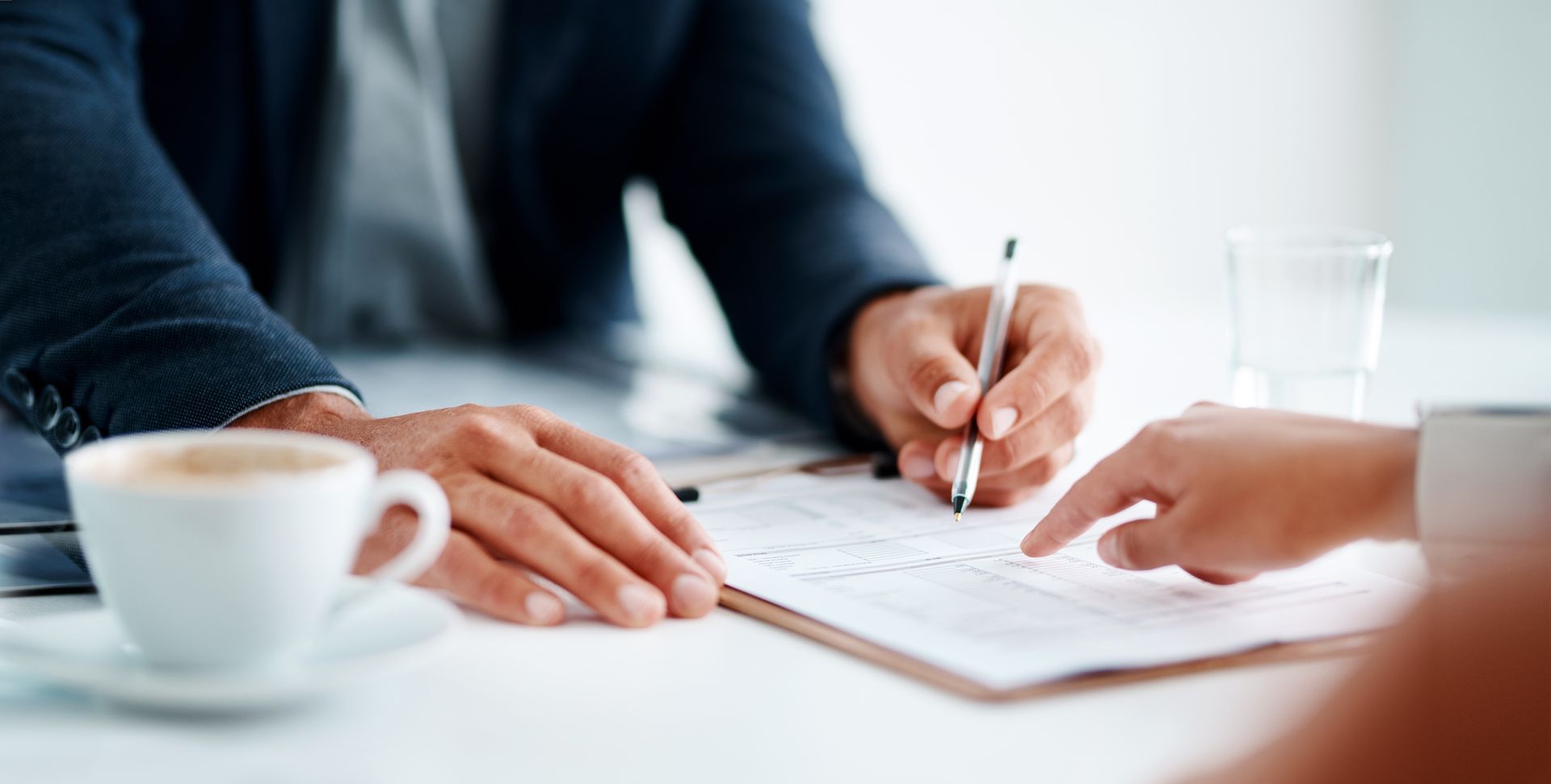 A worker in orange vest and blue helmet using a suction lifter to install a large pane of glass.