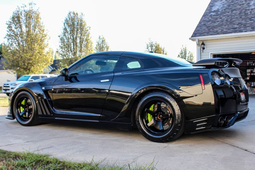 A black sports car is parked in front of a garage.