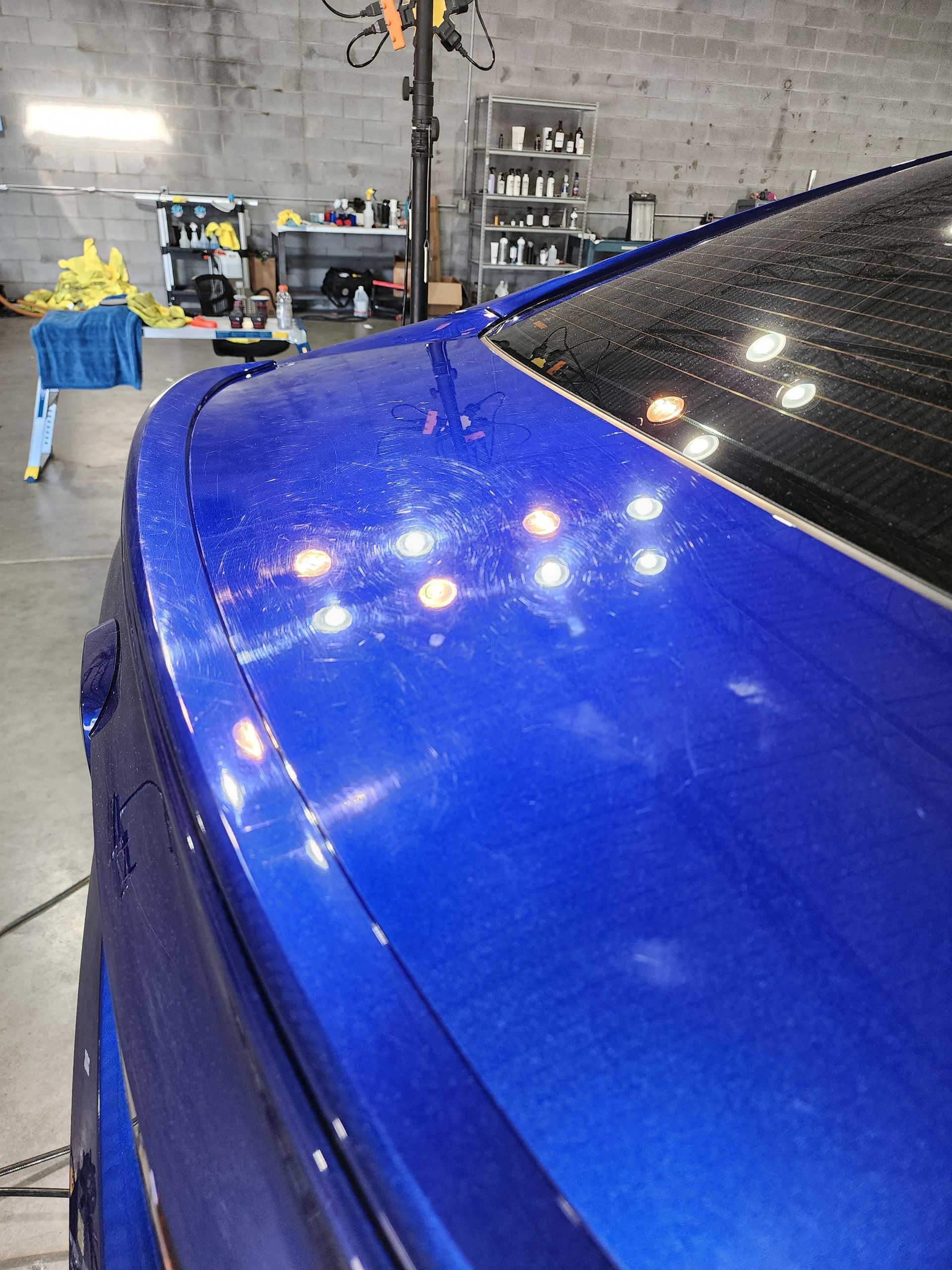 A close up of a blue car 's hood in a garage.