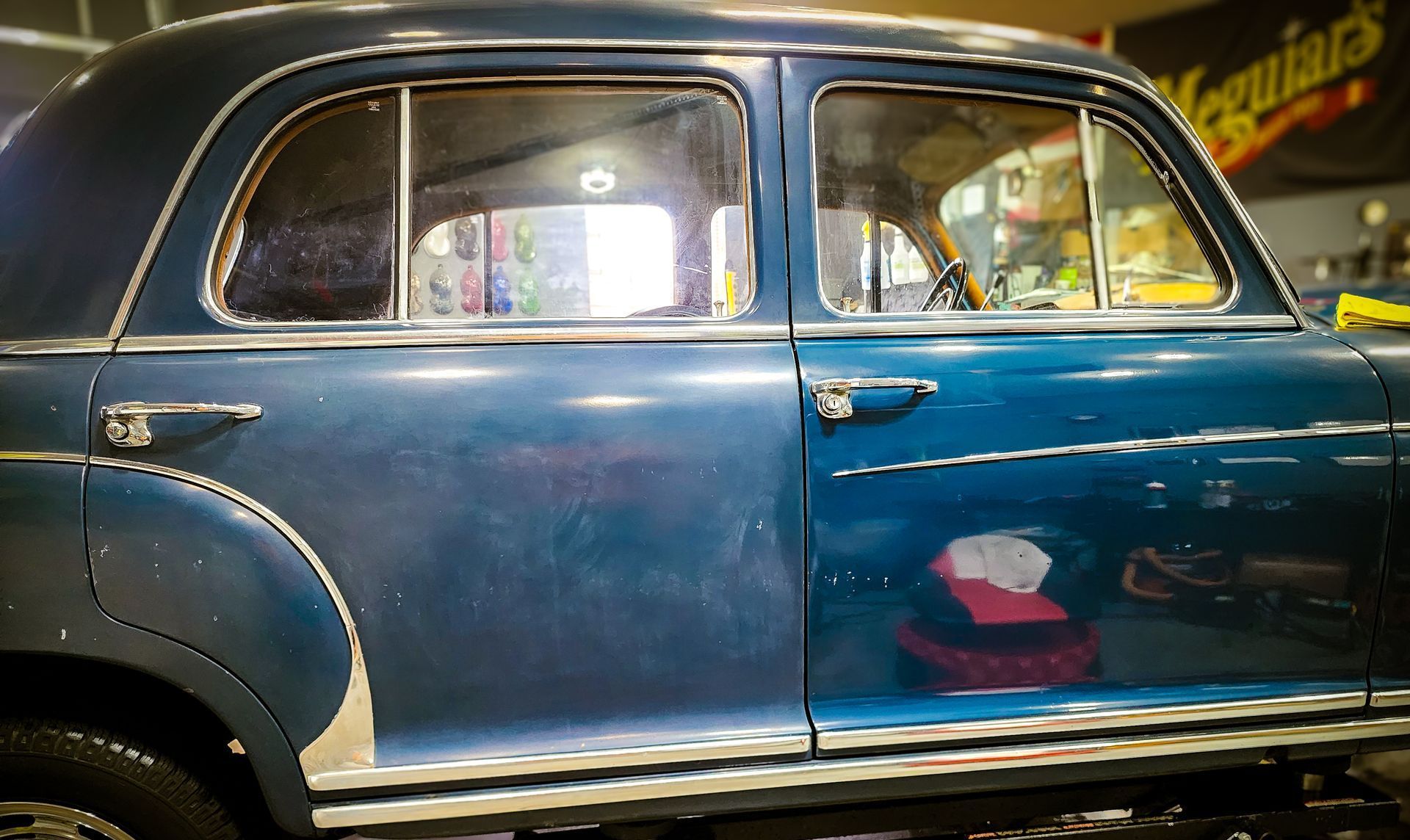 A blue vintage Mercedes S220 showing a before and after paint correction on the doors