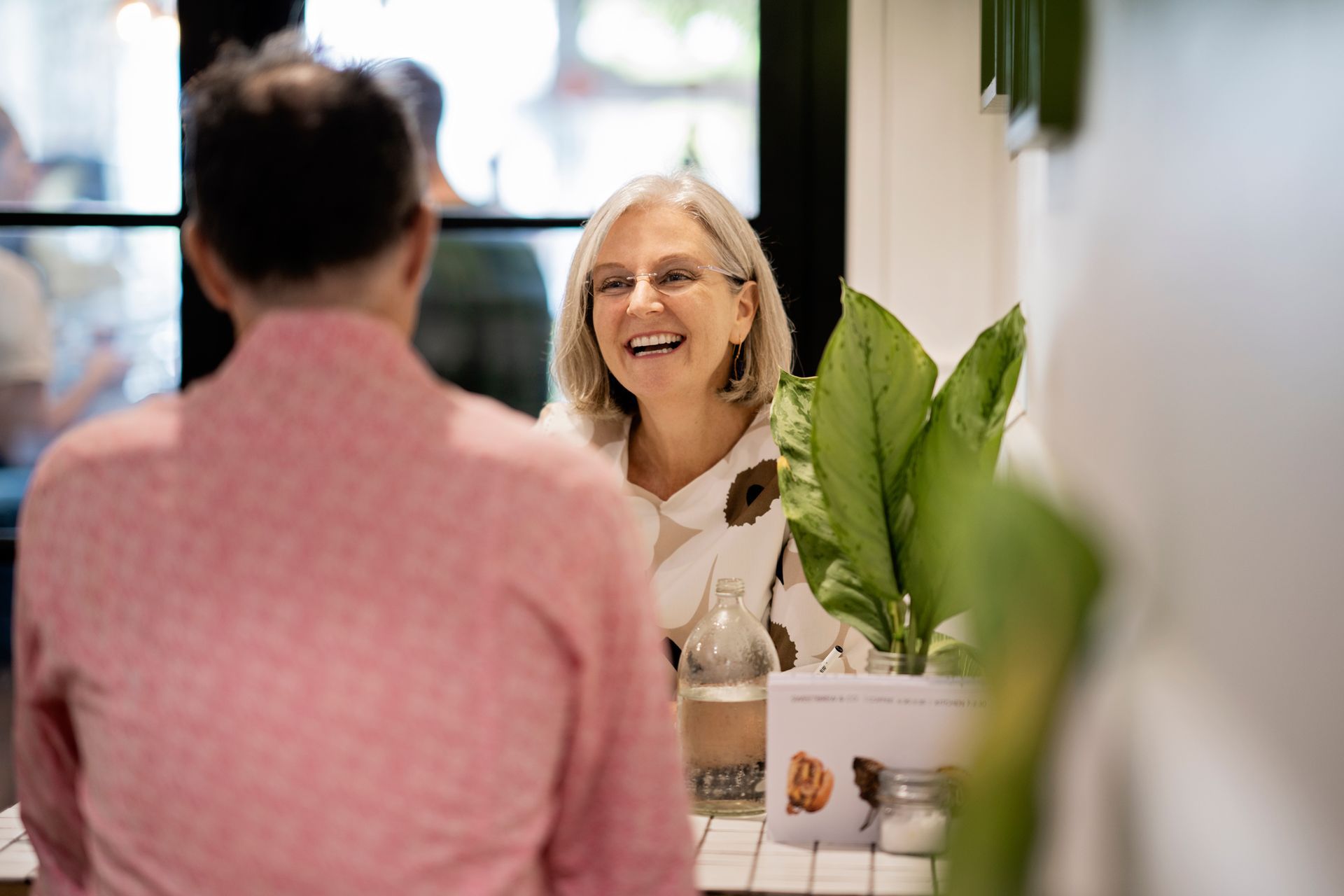 A man and a woman are sitting at a table talking to each other.