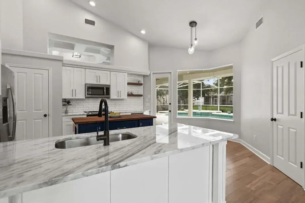 A kitchen with white cabinets , granite counter tops , stainless steel appliances and a large island.