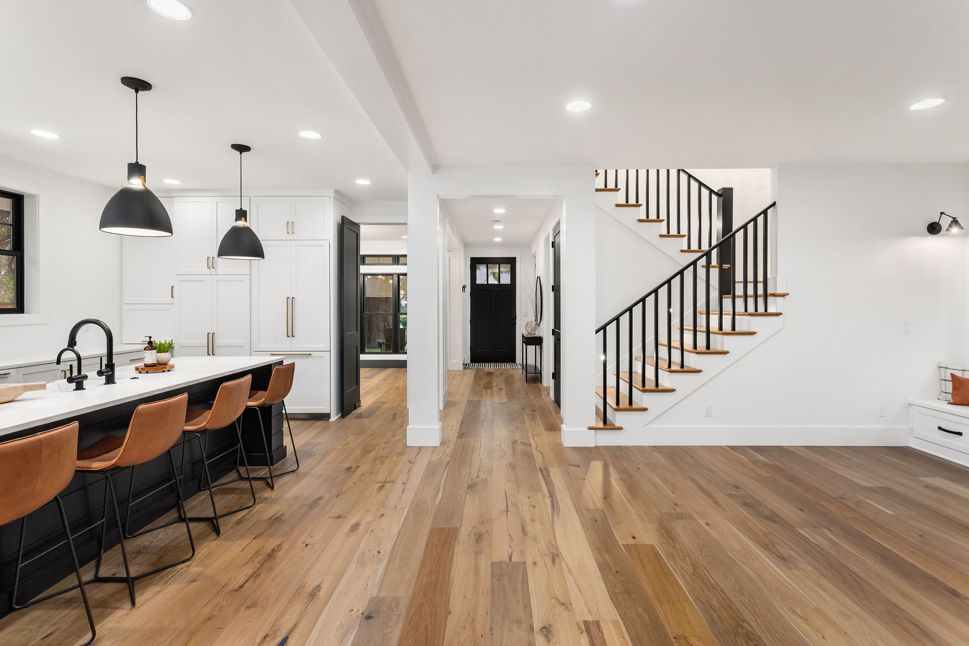 A kitchen with a wooden floor and stairs leading up to the second floor.