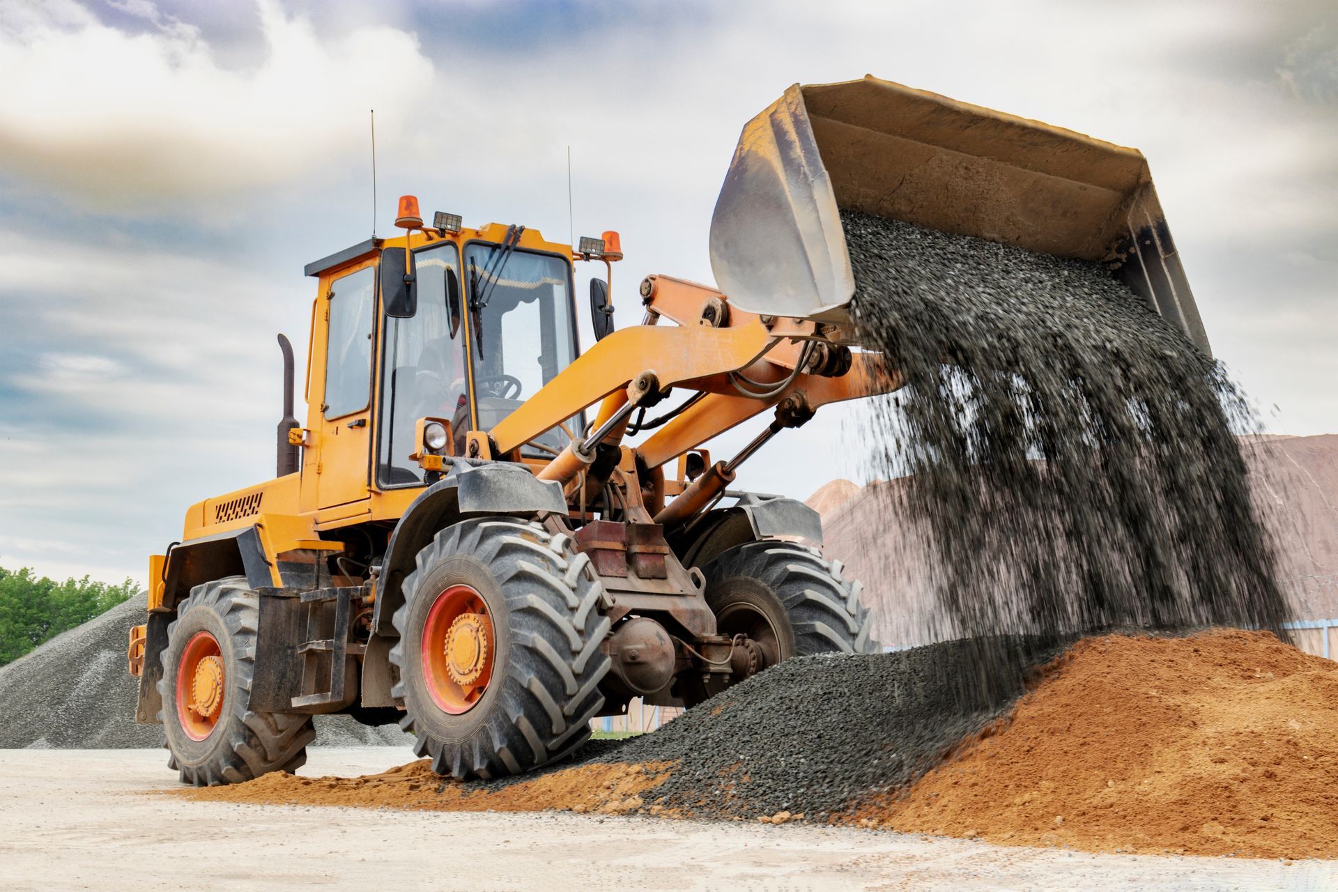 A bulldozer is loading gravel into a bucket on a construction site.