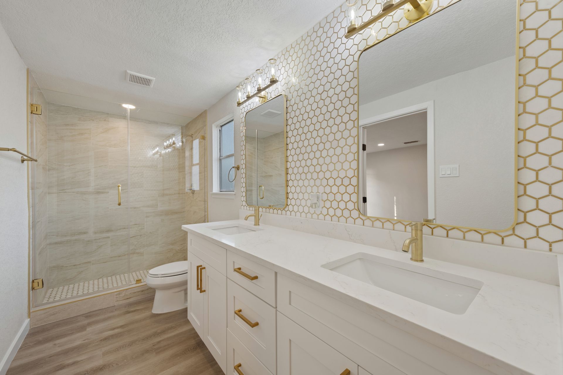 A bathroom with two sinks , a toilet and a shower.