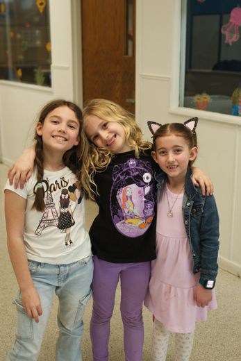 Group of people high-fiving outdoors in a grassy field. They are smiling, dressed in athletic wear.
