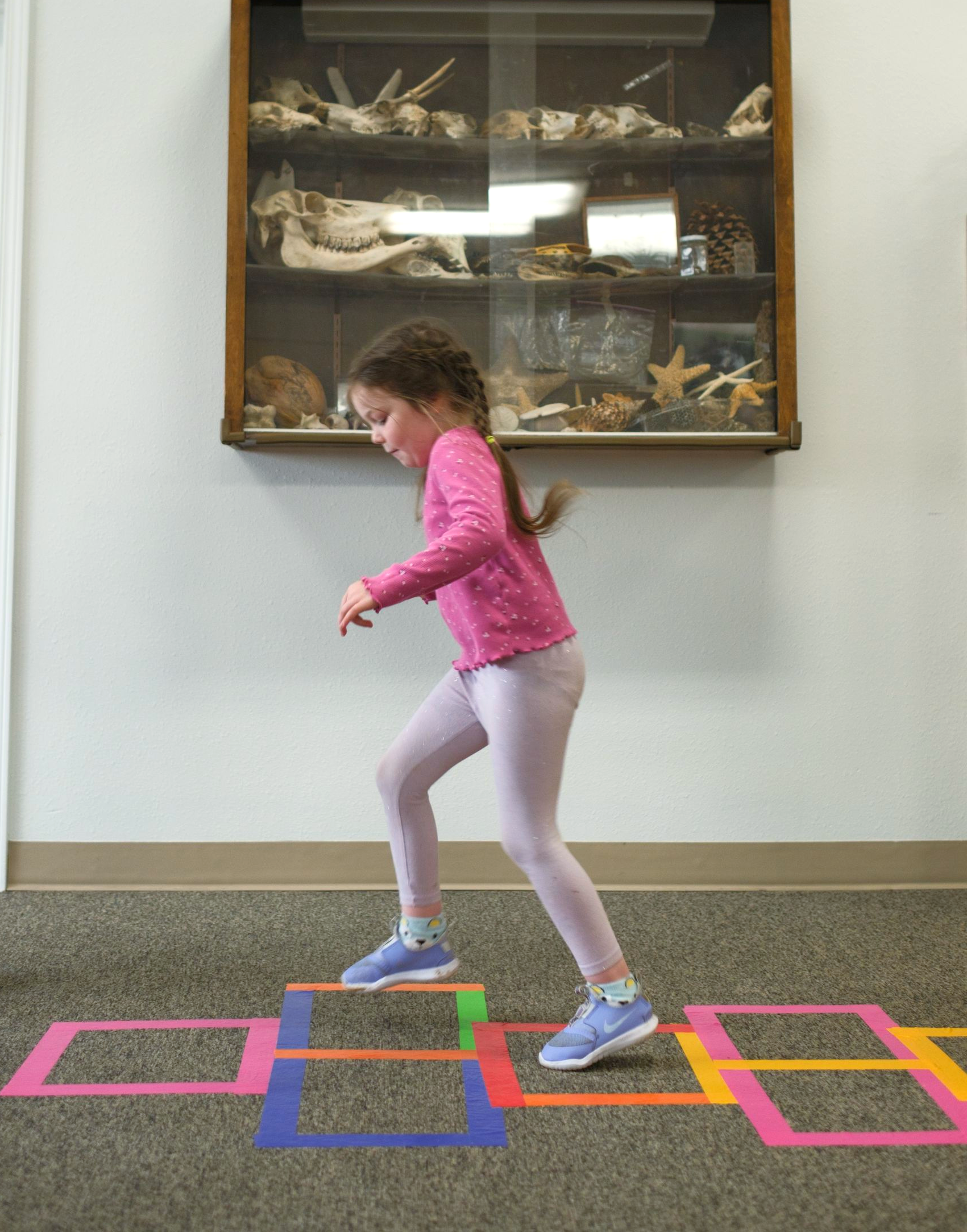 Two young people laughing in a field of green plants and yellow flowers.