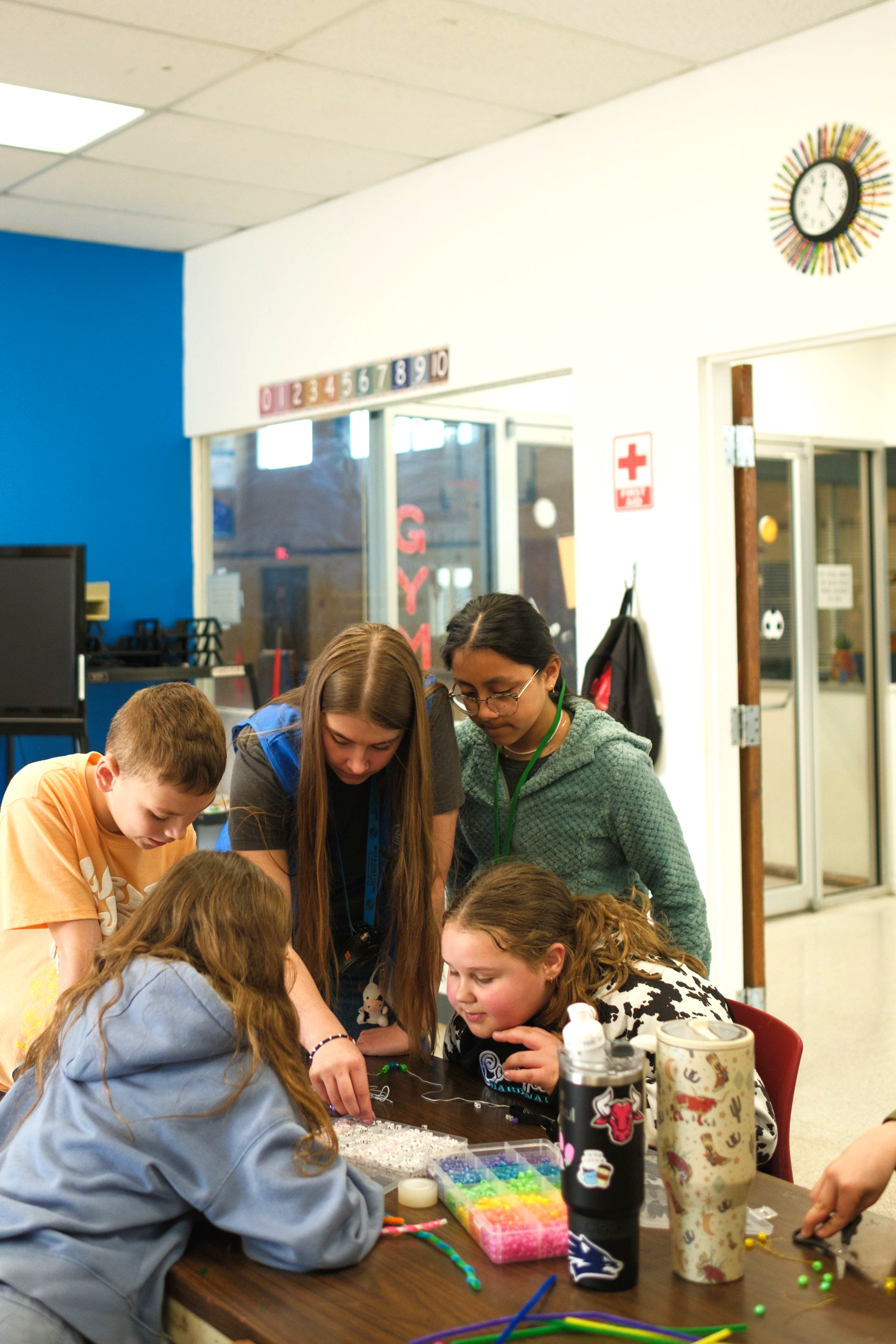 Group of people high-fiving outdoors in a grassy field. They are smiling, dressed in athletic wear.