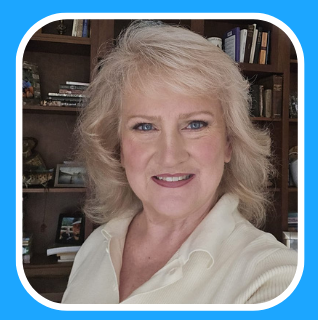Blond woman smiling, wearing a light-colored top, in front of a bookshelf.