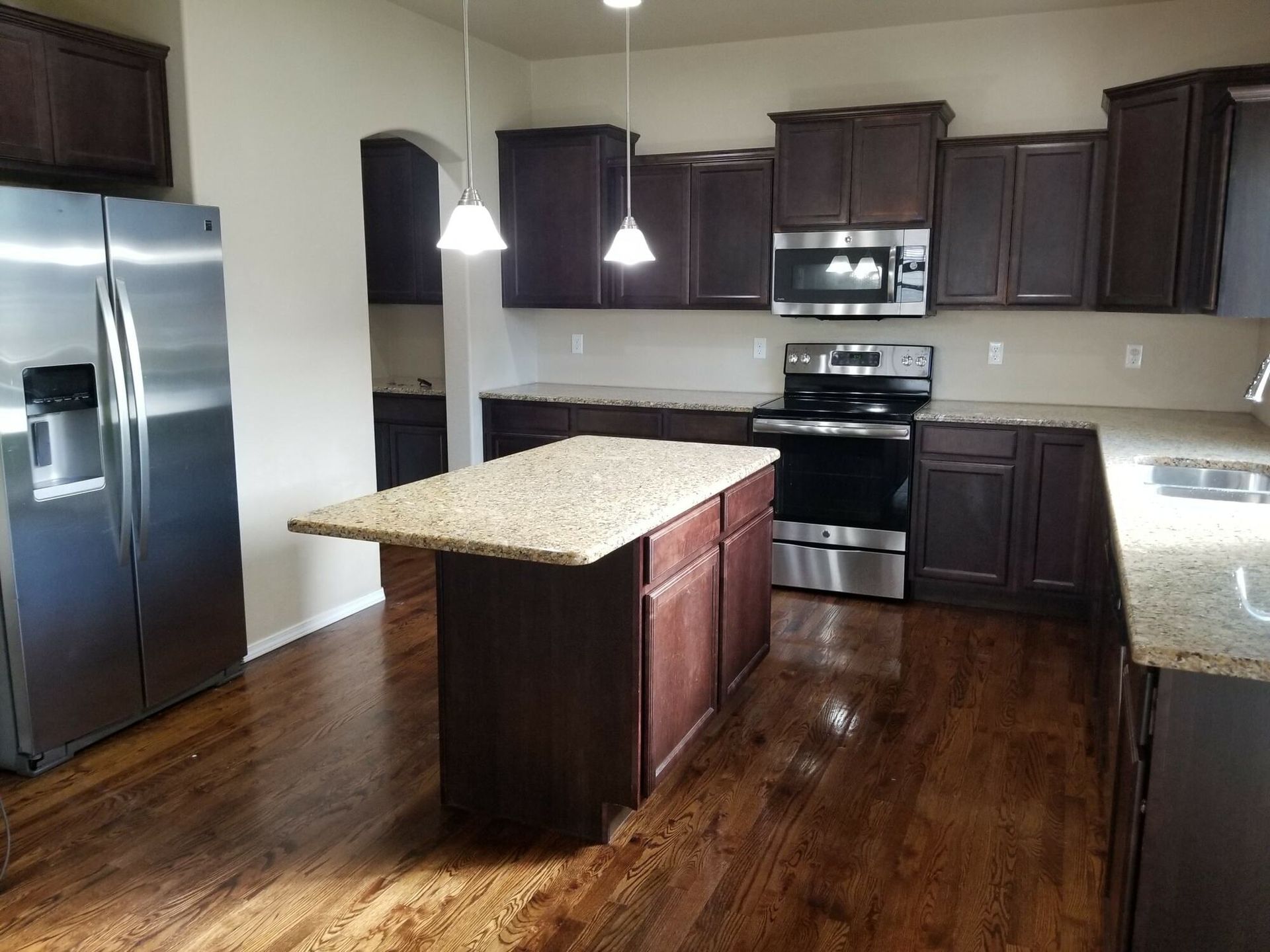 A kitchen with stainless steel appliances and a large island in the middle.