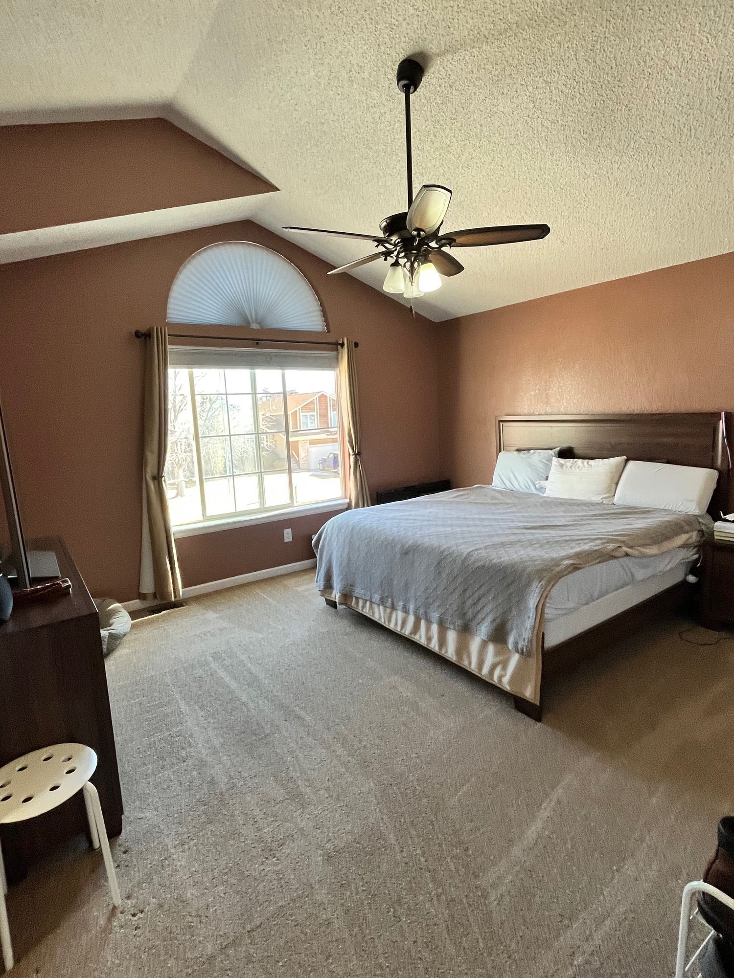 A bedroom with a large bed and a ceiling fan.