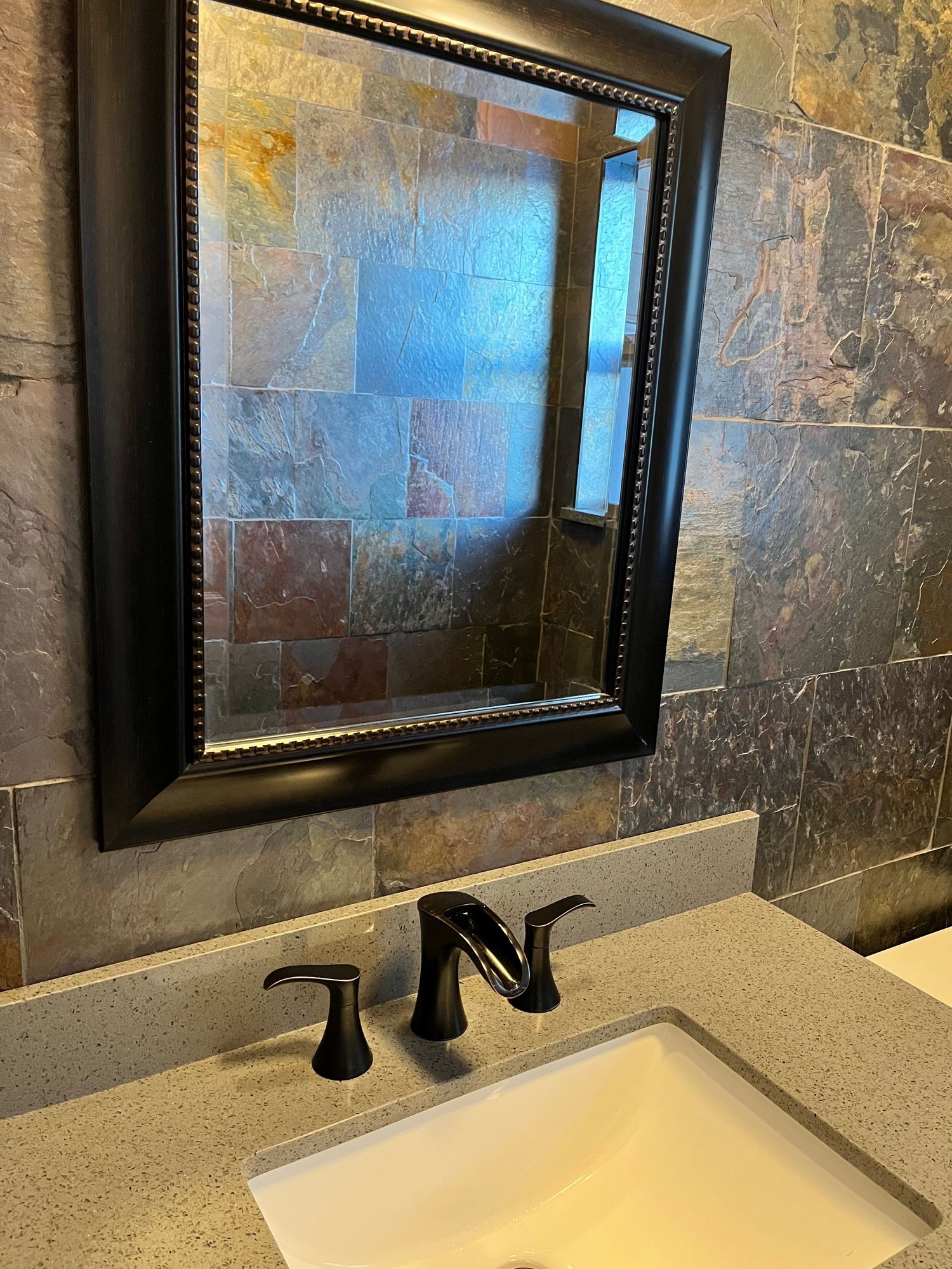 A bathroom with a sink , mirror and faucet.